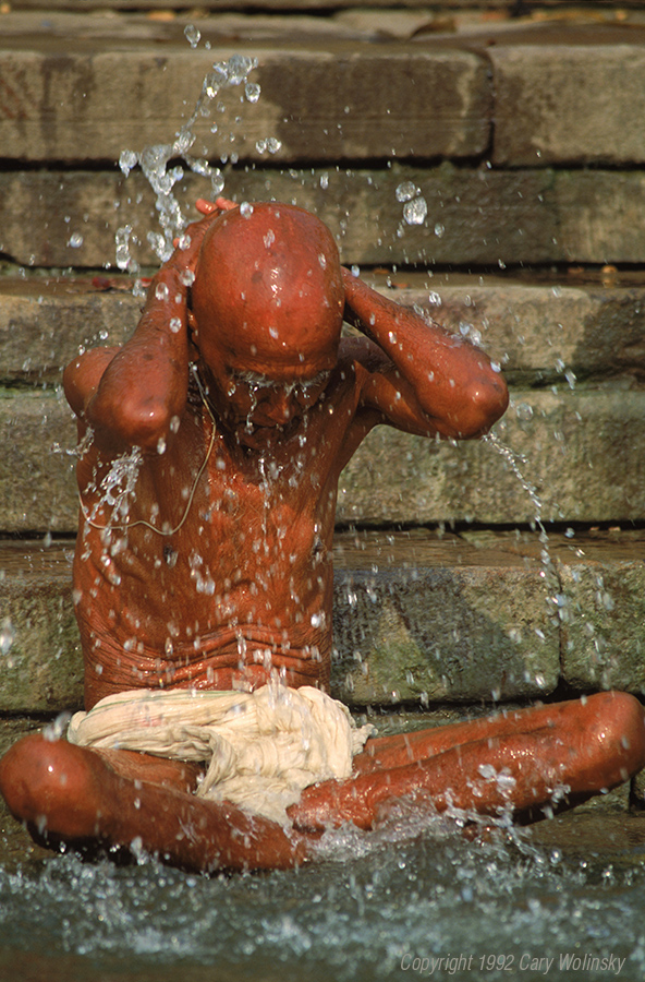 A Indian Hindu holy man performing a customary act of bathing in the Ganges river to cleanse his soul. Varanasi (Benares), India. He is wearing a sutra or sacred thread.