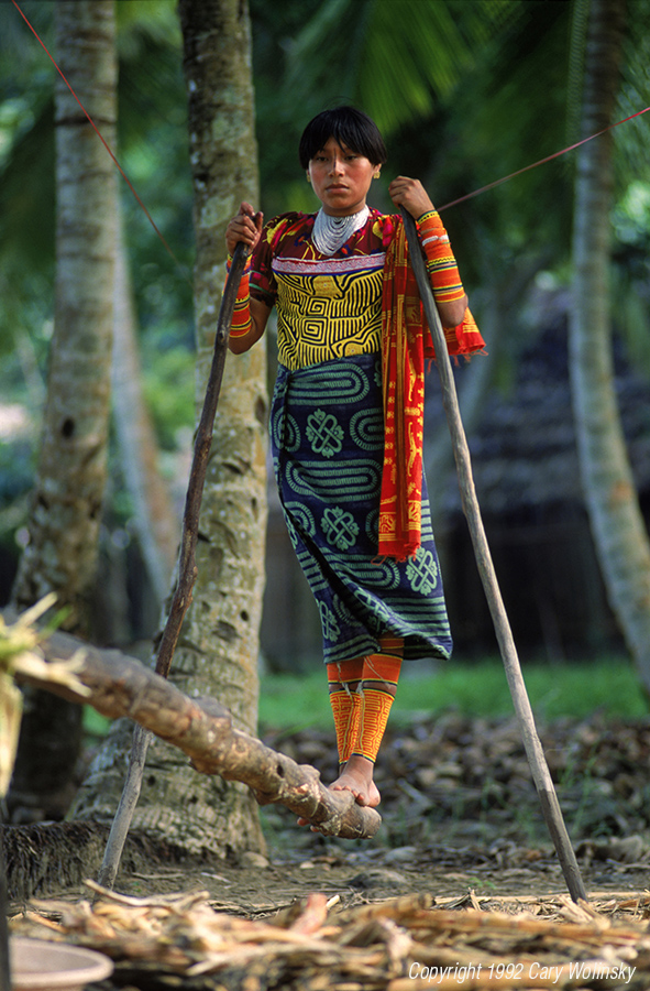San Blas Islands, Panama. Kuna Indian woman wearing a mola (appliqué blouse) works a traditional sugarcane press. 