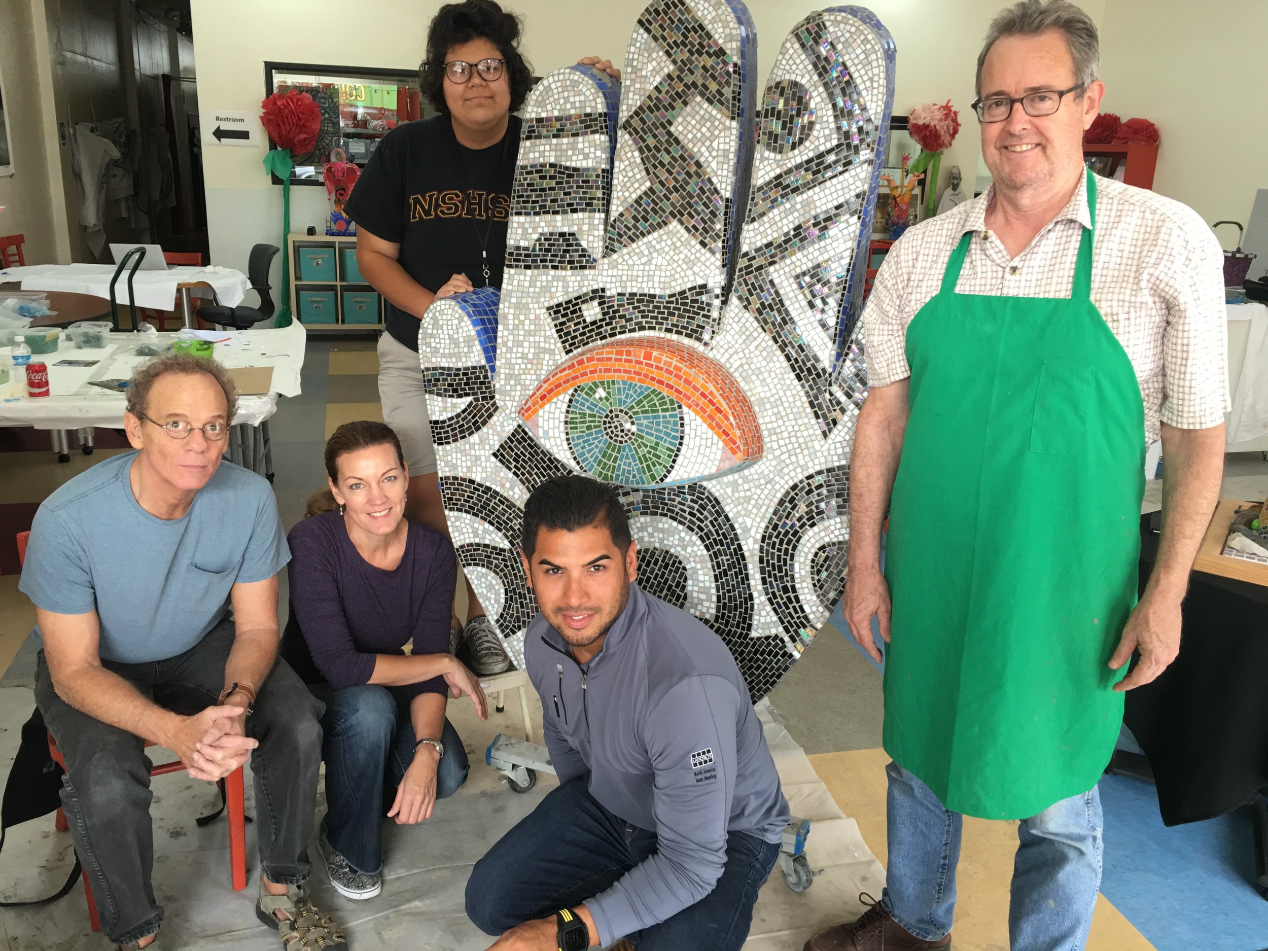 Joe Stokes, lead art instructor, Julie Richey, lead mosaic artist, Maria Patino, student intern, Daniel Diaz, Laticrete rep, and Kelly Nash, 29 Pieces staff artist pose with the completed hand.