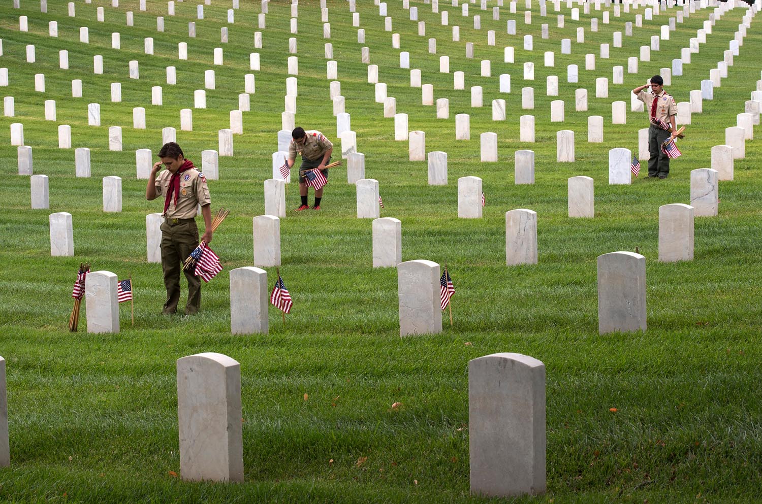  From left, Boy Scouts Troop 400, Dakota Hansen, 14, Christian Pinn, 14, and Kenny Grijalva, 15, place American flags, say the names and render salutes at the Los Angeles National Cemetery on Saturday. Hundreds of L.A. area Boy Scouts, Girls Scouts, 