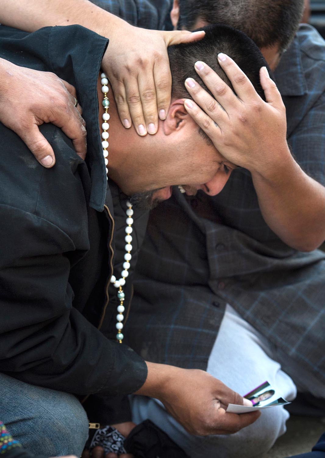  Surrounded by family, Rudy Coronado cries as he holds photos of his daughters. Three children were found dead in their home, allegedly killed by their mother, Carol Coronado. More than 80 family members, friends and neighbors prayed at a vigil Wedne