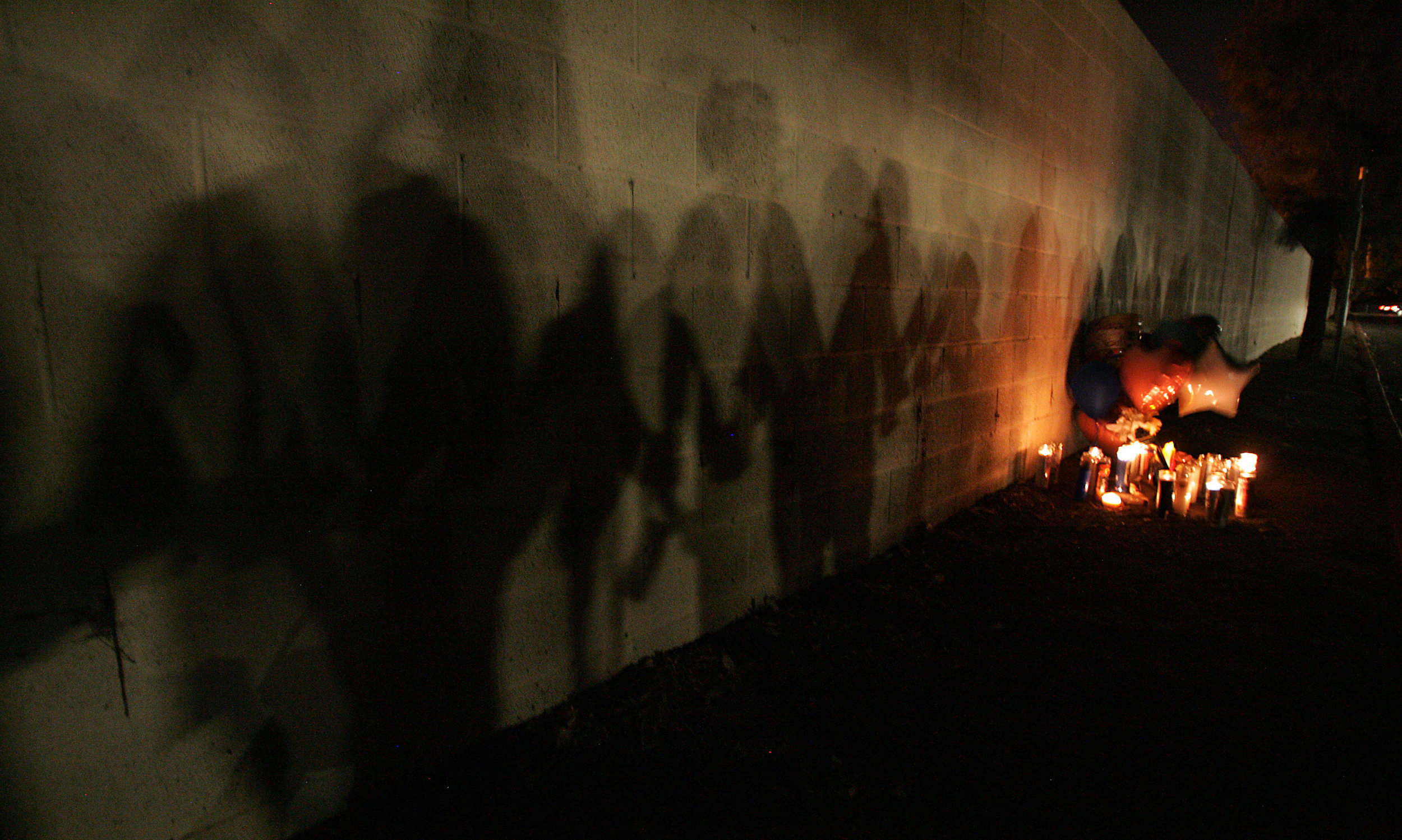  THe shadows of family and friends as they hold a candle light vigil for Isaac Kelly, 33, who was shot and killed by a security guard just after midnight in an apartment complex in the 150 block of E. Nuevo Road Saturday in Perris, CA. October 3, 201