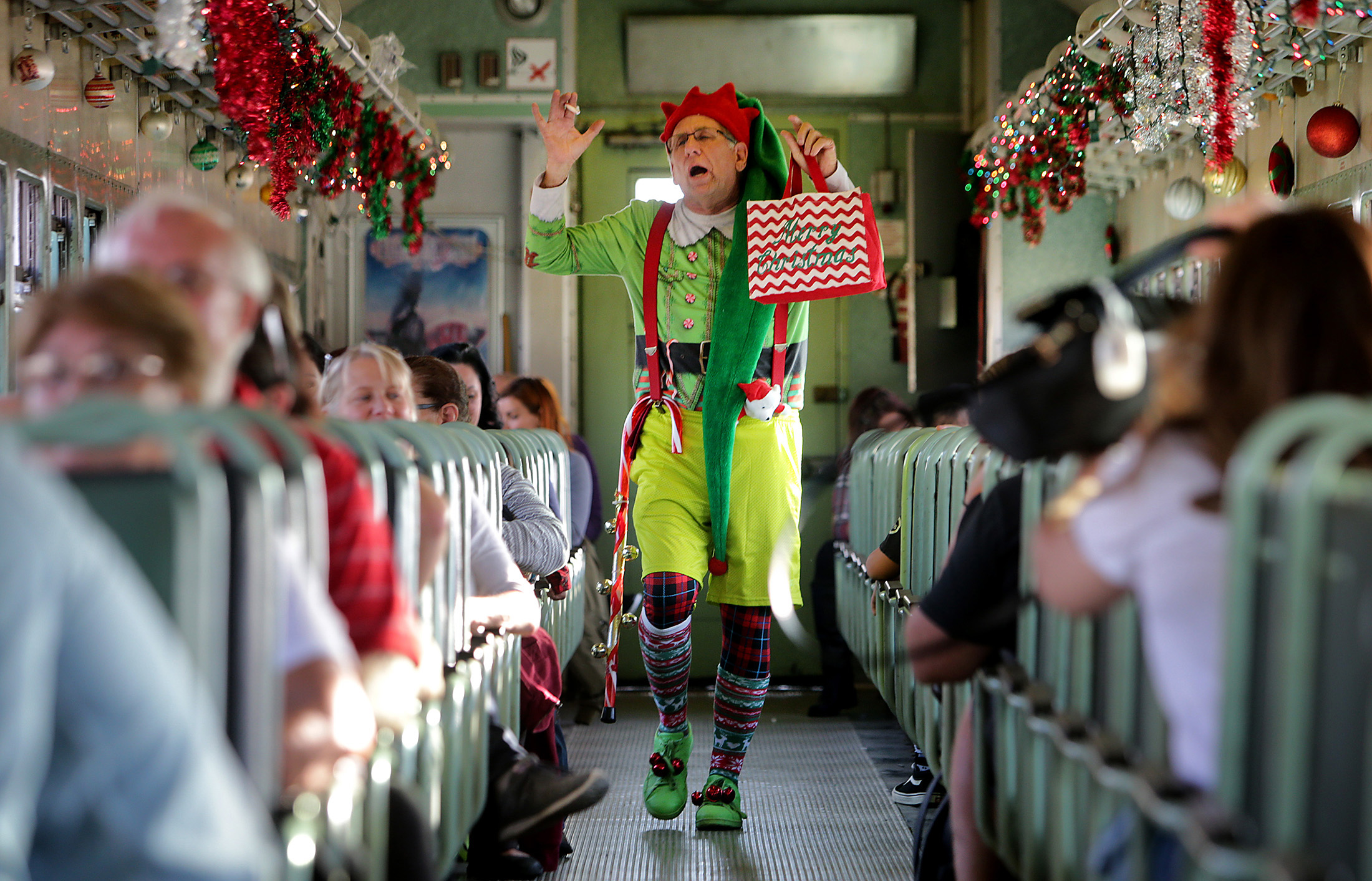  Ken Schwartz plays Jingles the elf as he sings and dances for guests on the train during "Take a Train to Santa’s Workshop" at Orange Empire Railway Museum Sunday in Perris, CA. December 3, 2017. 
 