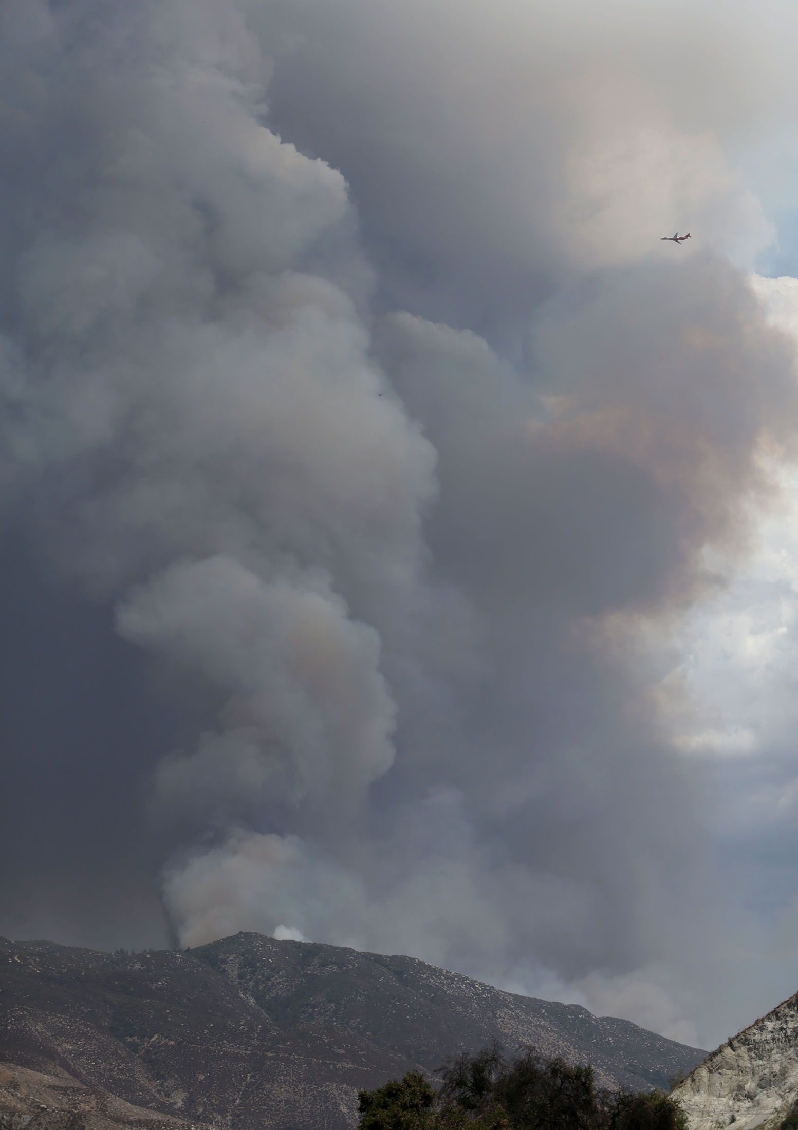  A tanker is dwarfted by the plums of smoke from the fast moving Cranston fire as it grows to over 1,200 acres in the San Bernardino National Forest above Hemet on Wednesday, July 25, 2018.  