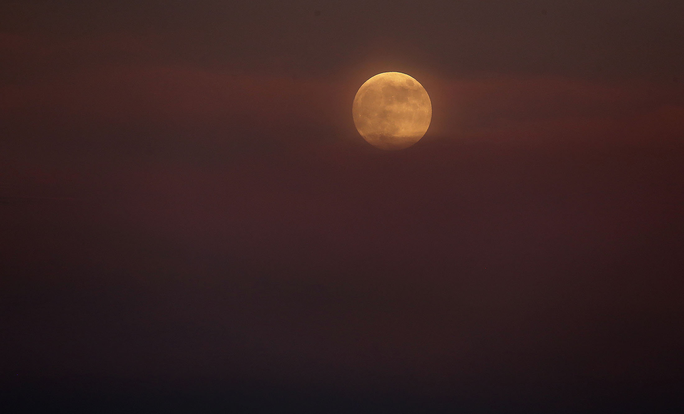  The full moon rises in the colorful smoke from the Cranston fire in the San Bernardino National Forest above Lake Hemet on Thursday, July 26, 2018. 
