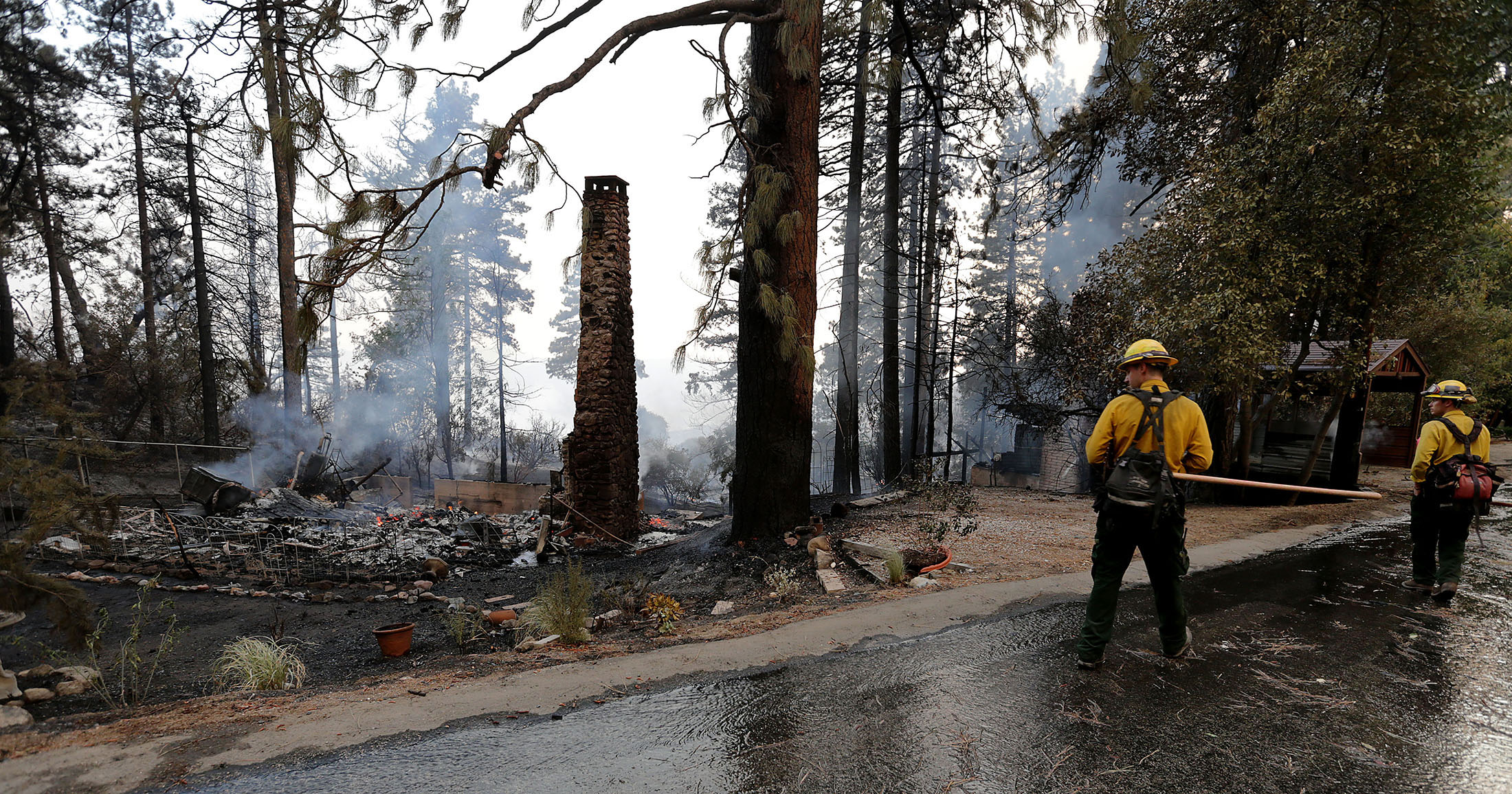  CalFire fighters walk past and look at one of the homes that was unable to be saved on Deer Foot Lane during the fast moving Cranston fire as it grows to more than over 3,500 acres in the San Bernardino National Forest in Idyllwild on Wednesday, Jul