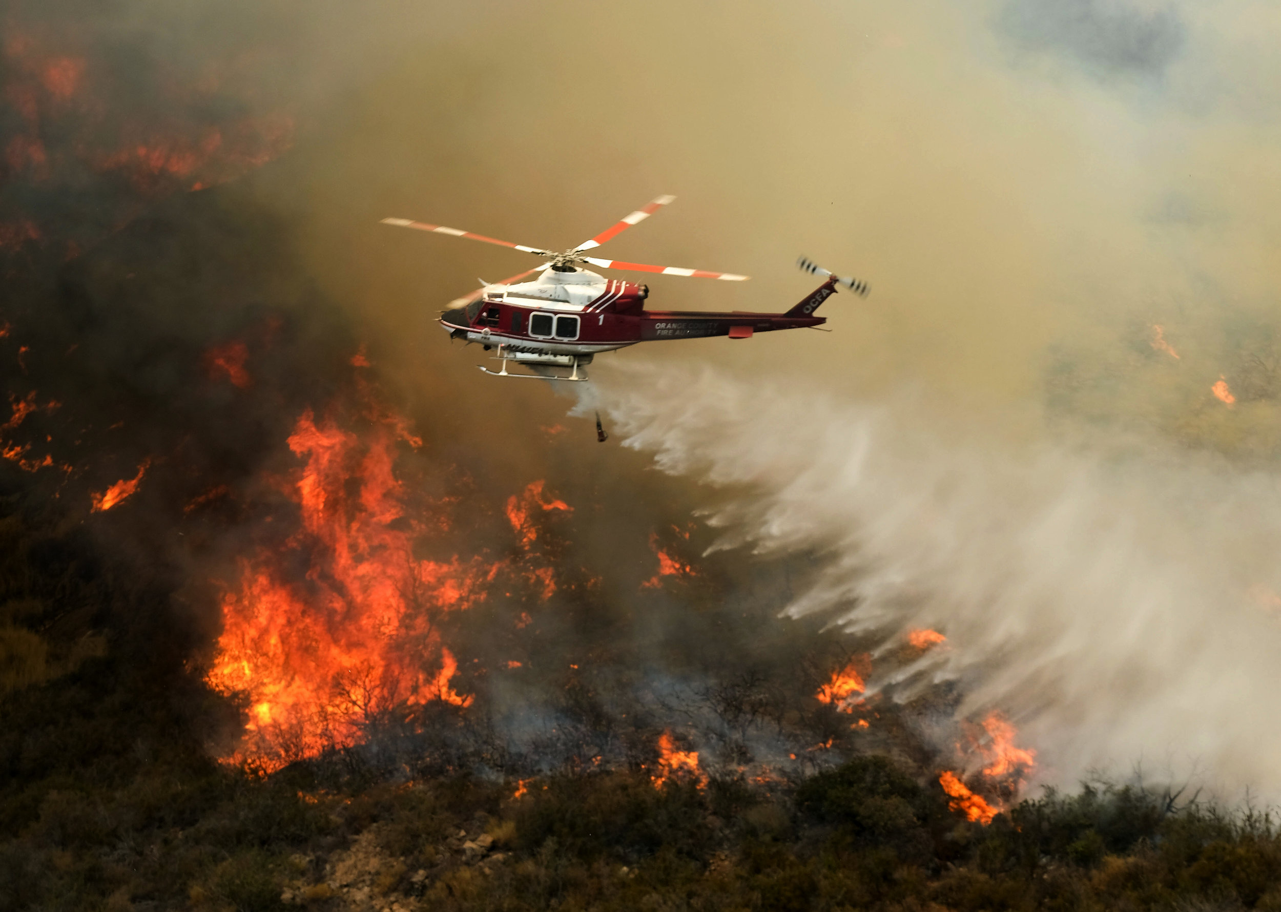  A helicopter drops water to a brush fire at the Holy Fire in Lake Elsinore, California, southeast of Los Angeles, on August 11, 2018. The fire has burned 21,473 acres and was 29 percent contained as of 8:30 a.m. Saturday, according to the Cleveland 