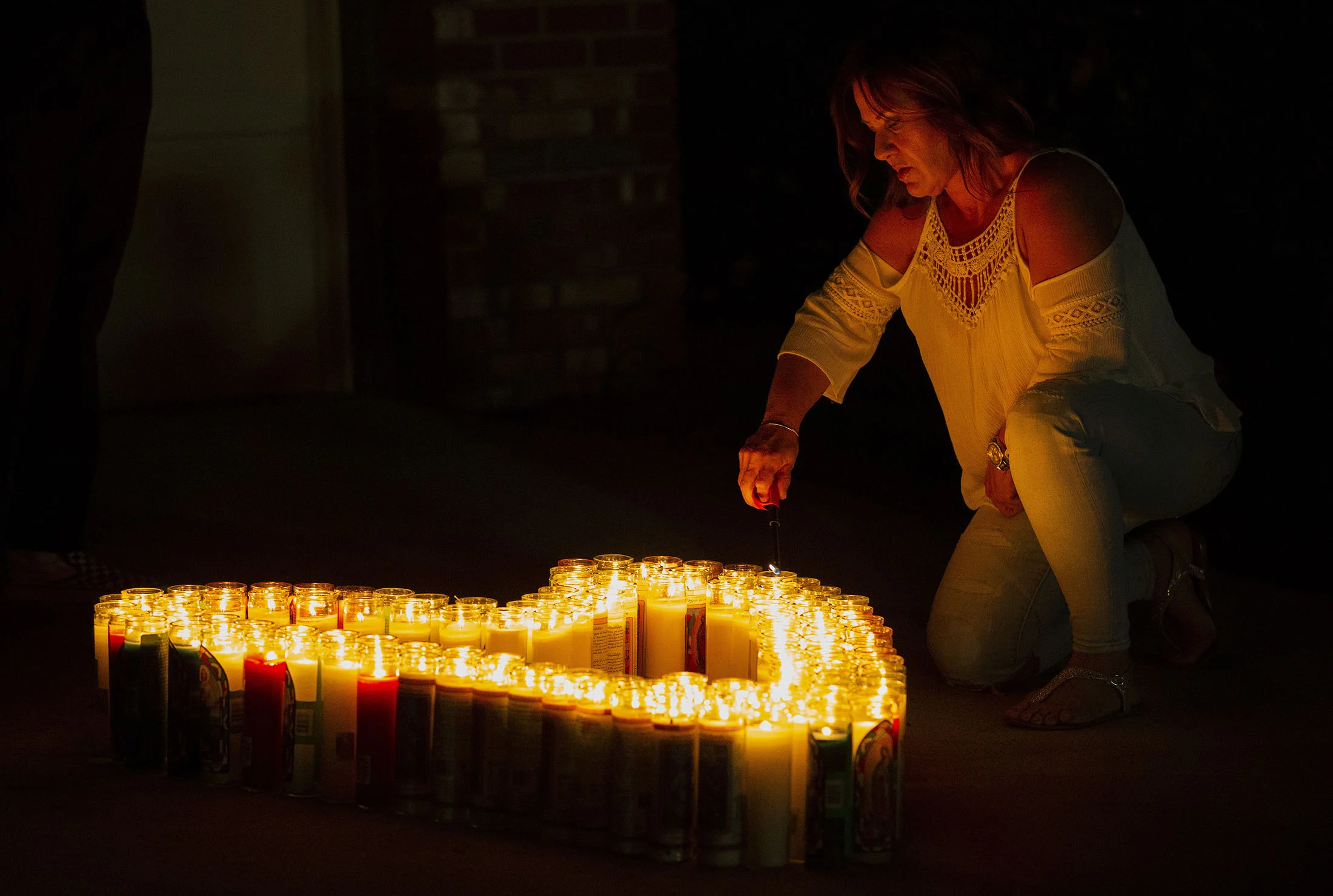 A woman lights candles in the shape of the heart during a candlelight vigil for Leslie Pray, 54, who was killed Saturday while riding her bike along Mills Avenue near Radcliffe Drive in Claremont on Monday, November 5, 2018.