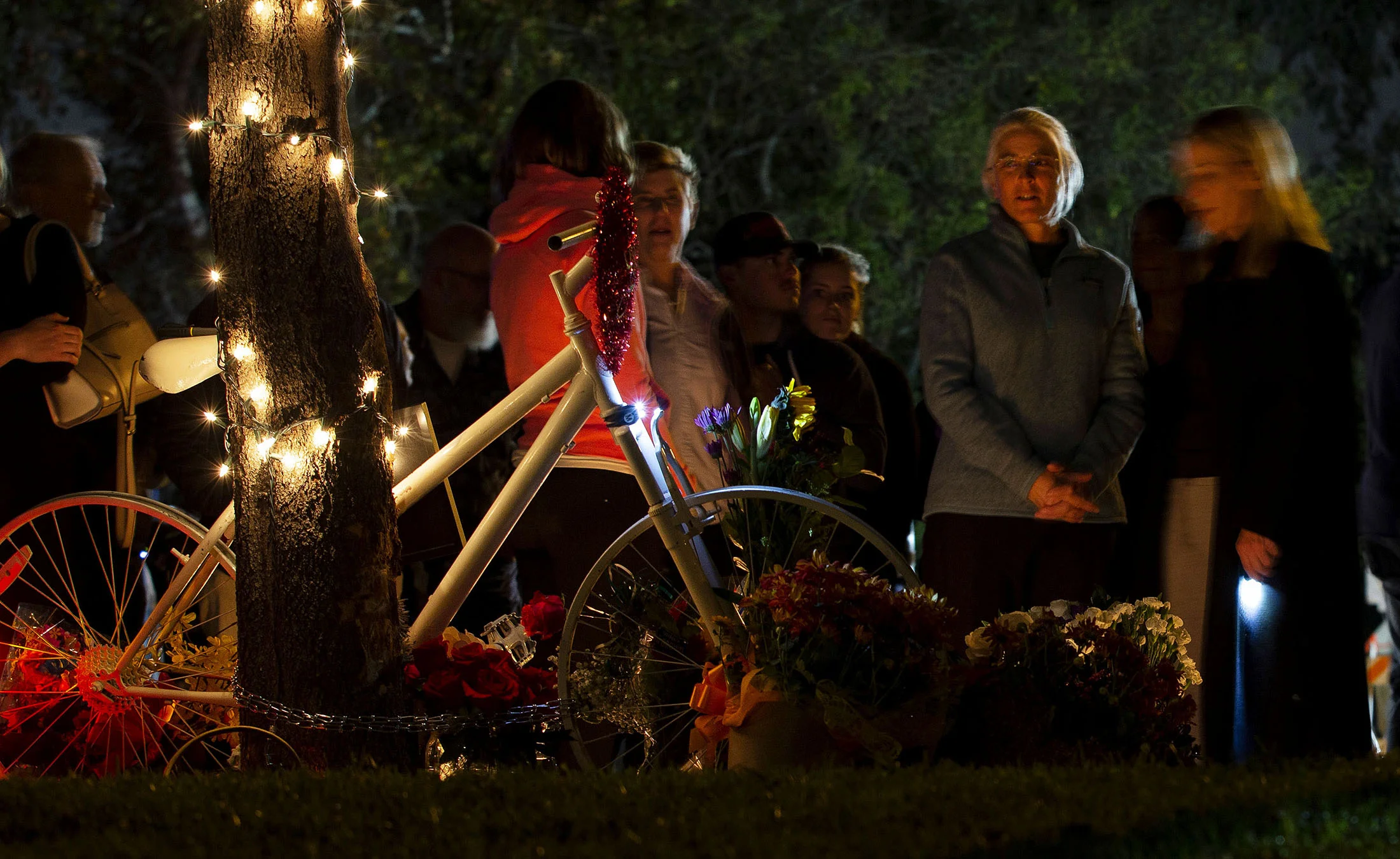 Betsy Hipple, second from right, life partner of Leslie Pray, 54, who was killed Saturday while riding her bike along Mills Avenue near Radcliffe Drive, looks over the ghost bike during a candle light vigil to honor Pray in Claremont on Monday, November 5, 2018.