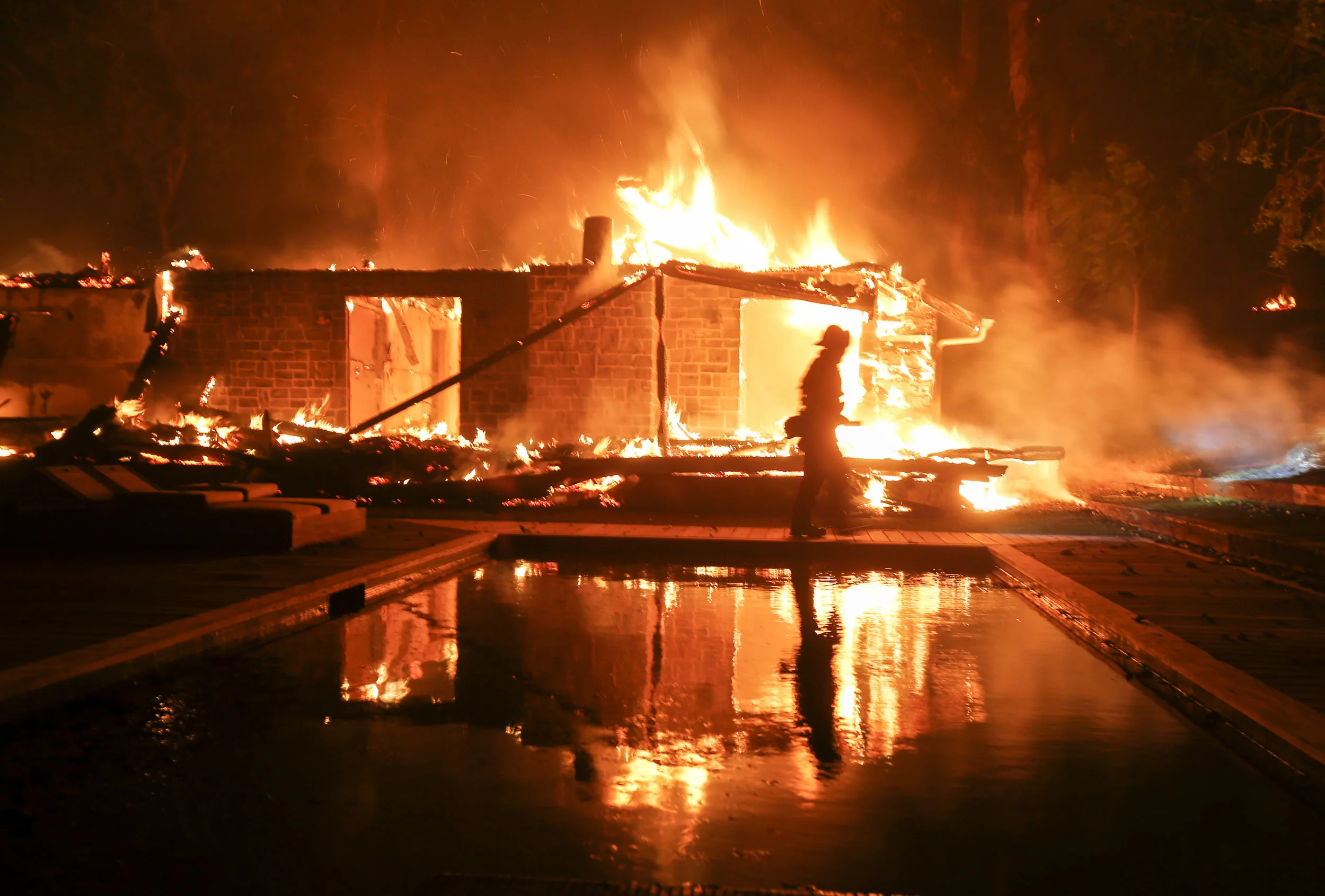  A firefighter walks by the a burning home in Malibu, Calif., Friday, Nov. 9, 2018. 