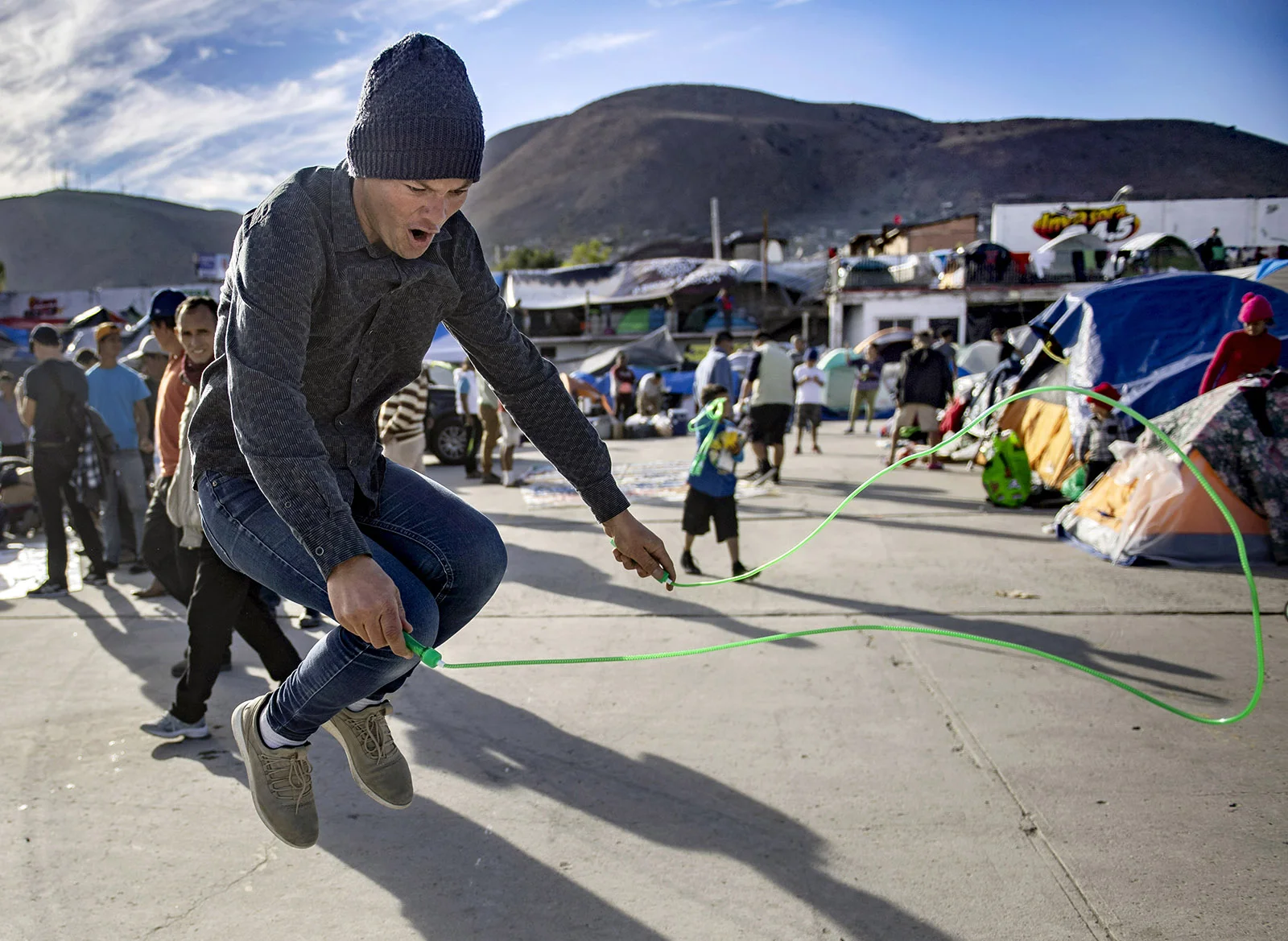 A man puts his new jump rope to use outside the El Barretal shelter after volunteers passed out toys and coloring books in Tijuana on Tuesday, December 4, 2018.