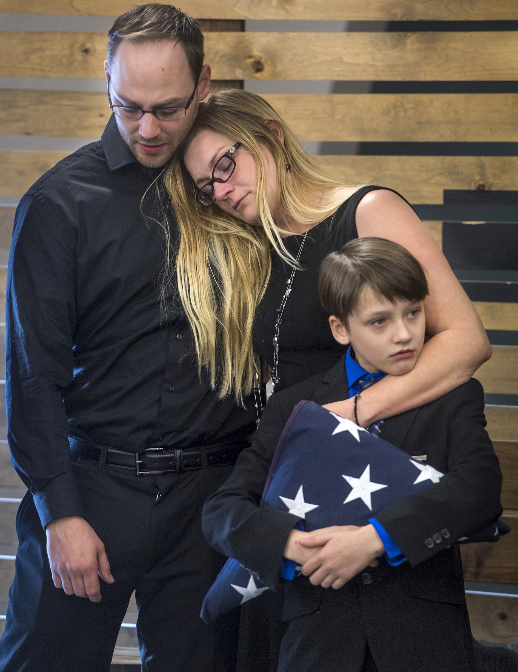 Mason Robinson, 11, holds the flag presented to him by Marines at the memorial service for his dad and two sisters who died in a house fire last week in rural Tennessee. Mason and his mom Elizabeth "Angel" Robinson, pictured, escaped the blaze. They