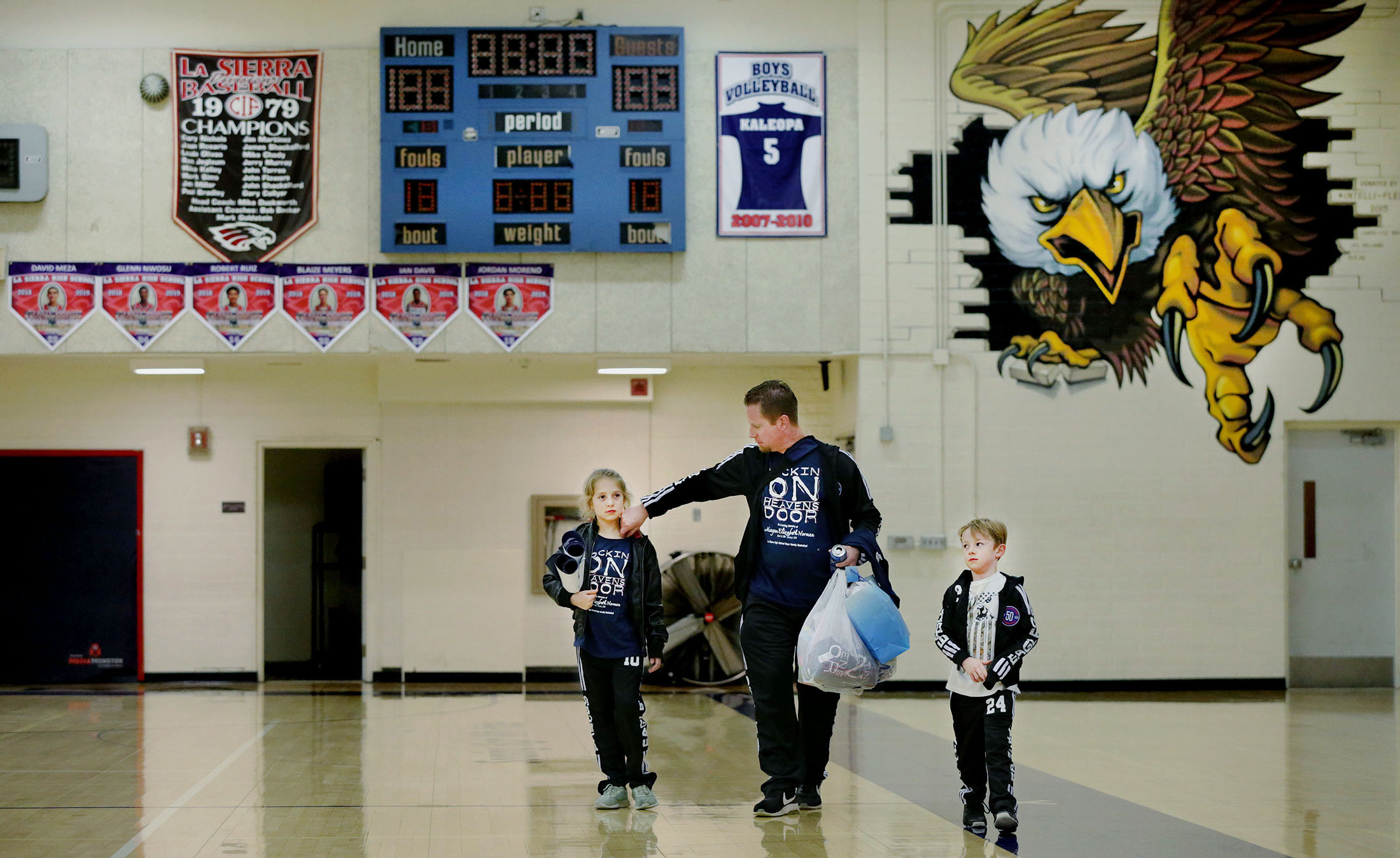 La Sierra boys basketball coach Justin Norman heads home with his children Juliya Norman, 9, left and Jake Norman, 5, after returning to the bench to coach the Eagles against Patriot 10 days after the sudden death of his wife, Meagan, with the help