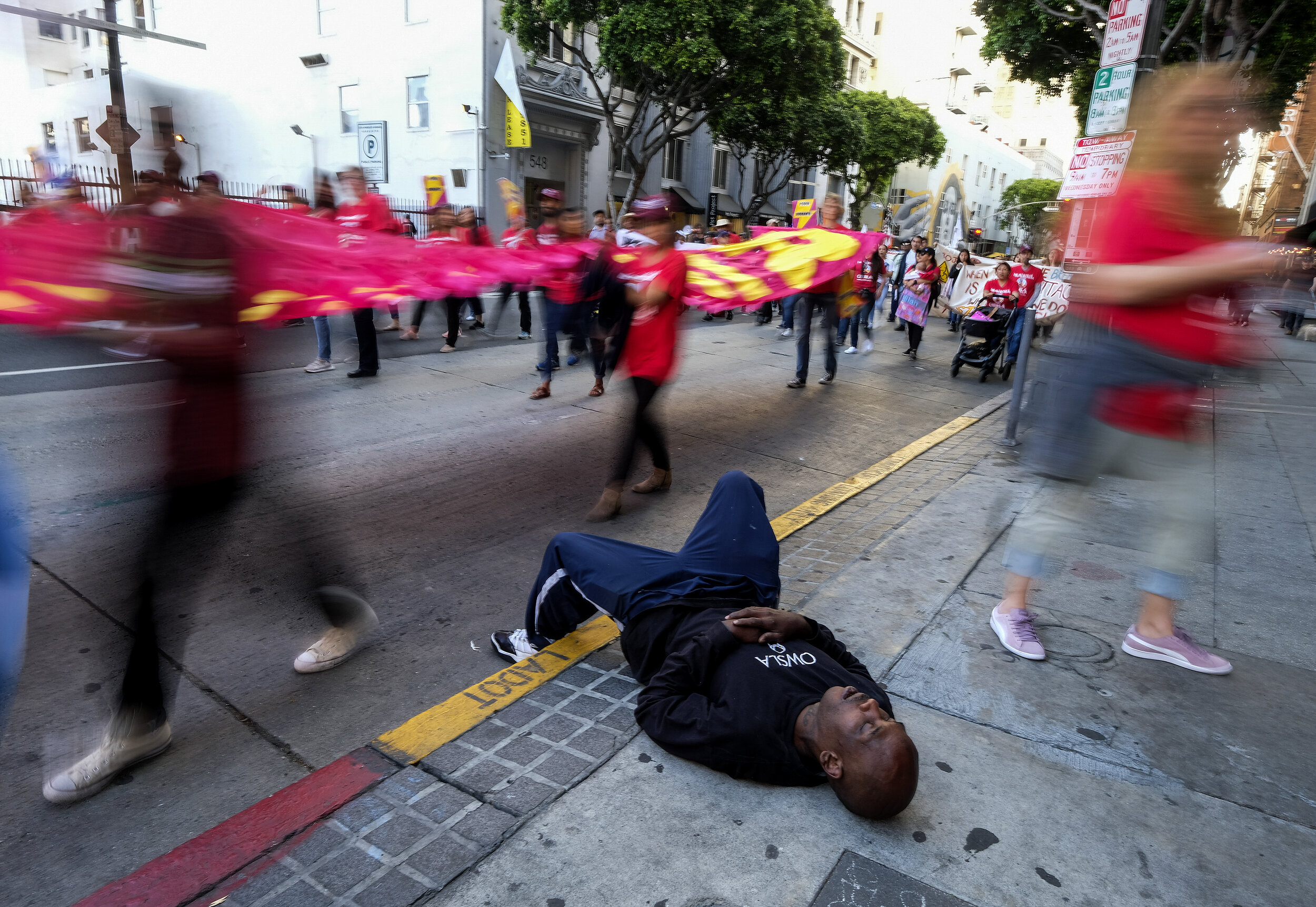  A homeless man sleeps on the sidewalk as thousands of workers rally on May Day in Los Angeles Wednesday, May 1, 2019. 