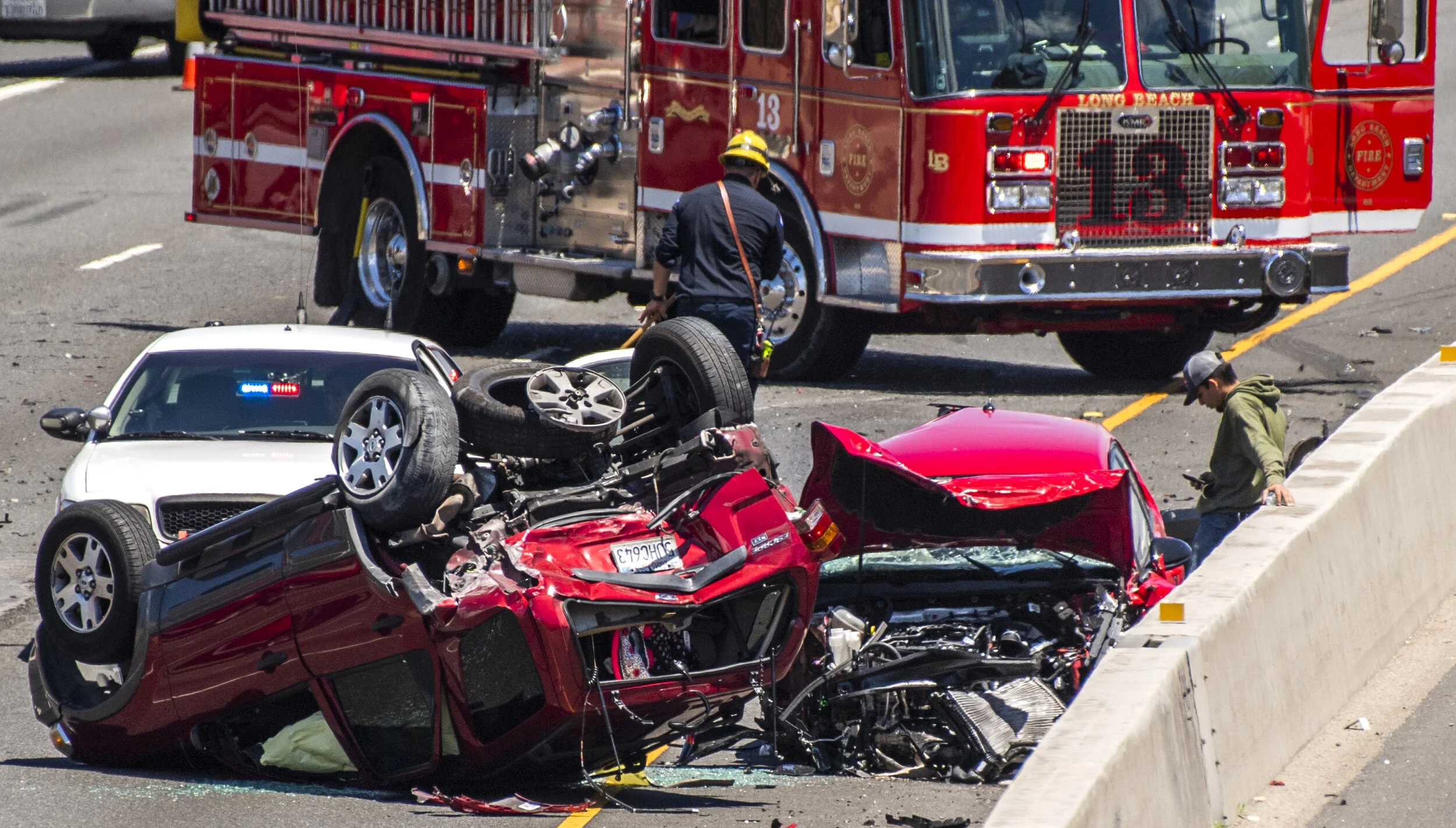  The only uninjured person stands next to a three-car crash that hurt four people, according to authorities.The wreck happened around 11 a.m., leaving one of the cars overturned in Long Beach Monday, May 20, 2019. Two of them had traumatic injuries, 