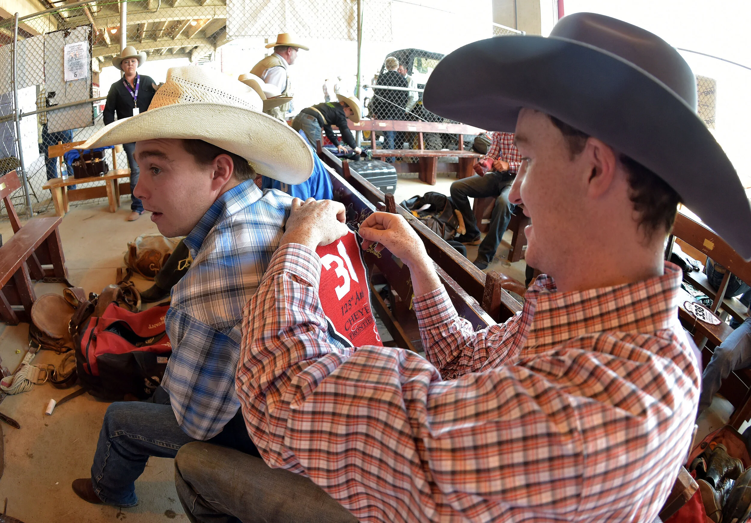  Rookie Saddle Bronc rider Jake Clark (right) pins Cooper Thatcher's (left) contestant number to his back in the cowboy ready area prior to the 123rd Cheyenne Frontier Days Rodeo in Cheyenne, Wyoming.  