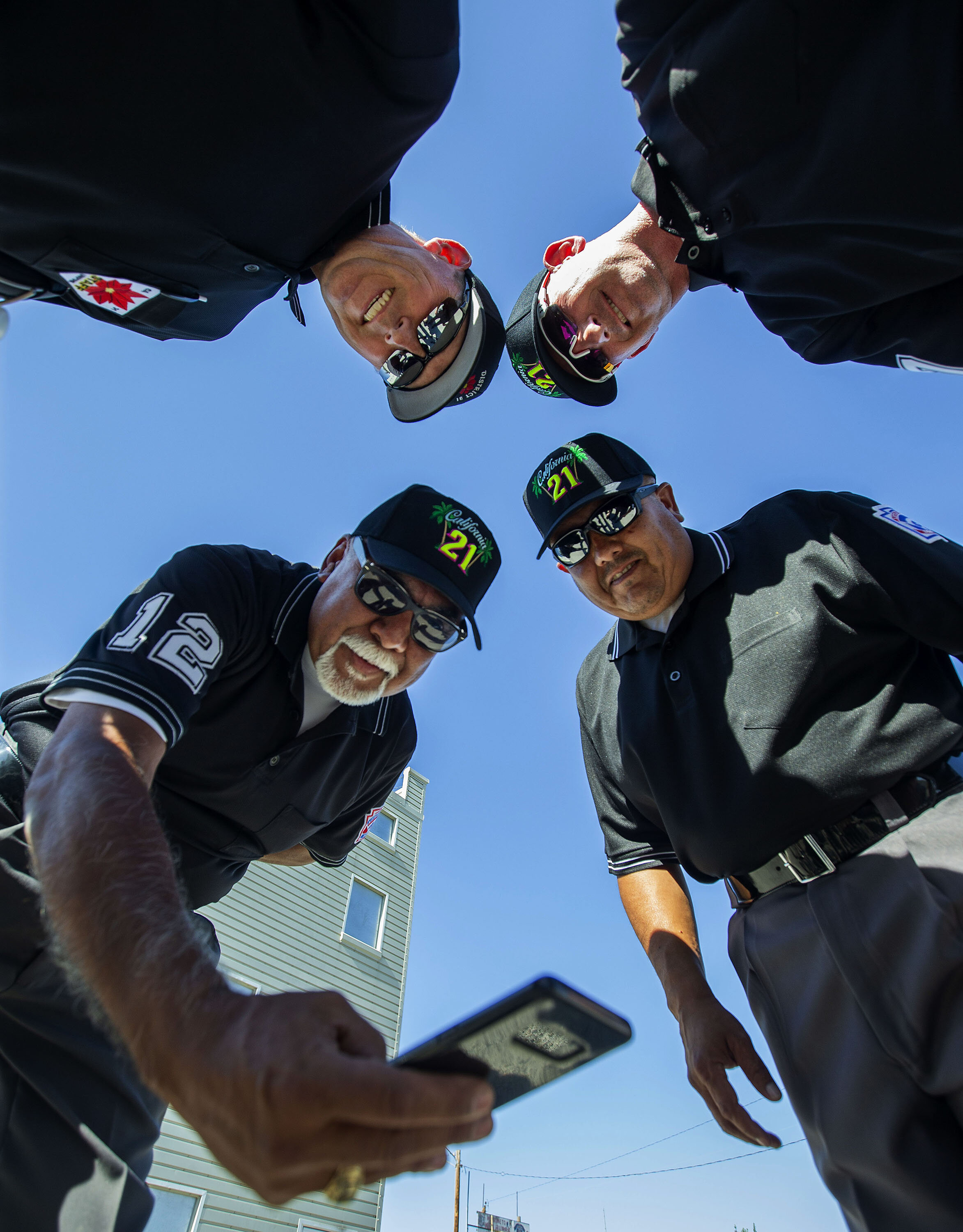 Little League umpires clockwise from bottom left: District 21-Anthony Estrada, District 31-Dave Miller, District 62-Chris Costlow and District 70-George Rodriguez pose for a cellphone group shot in the parking lot before heading to the field to umpi