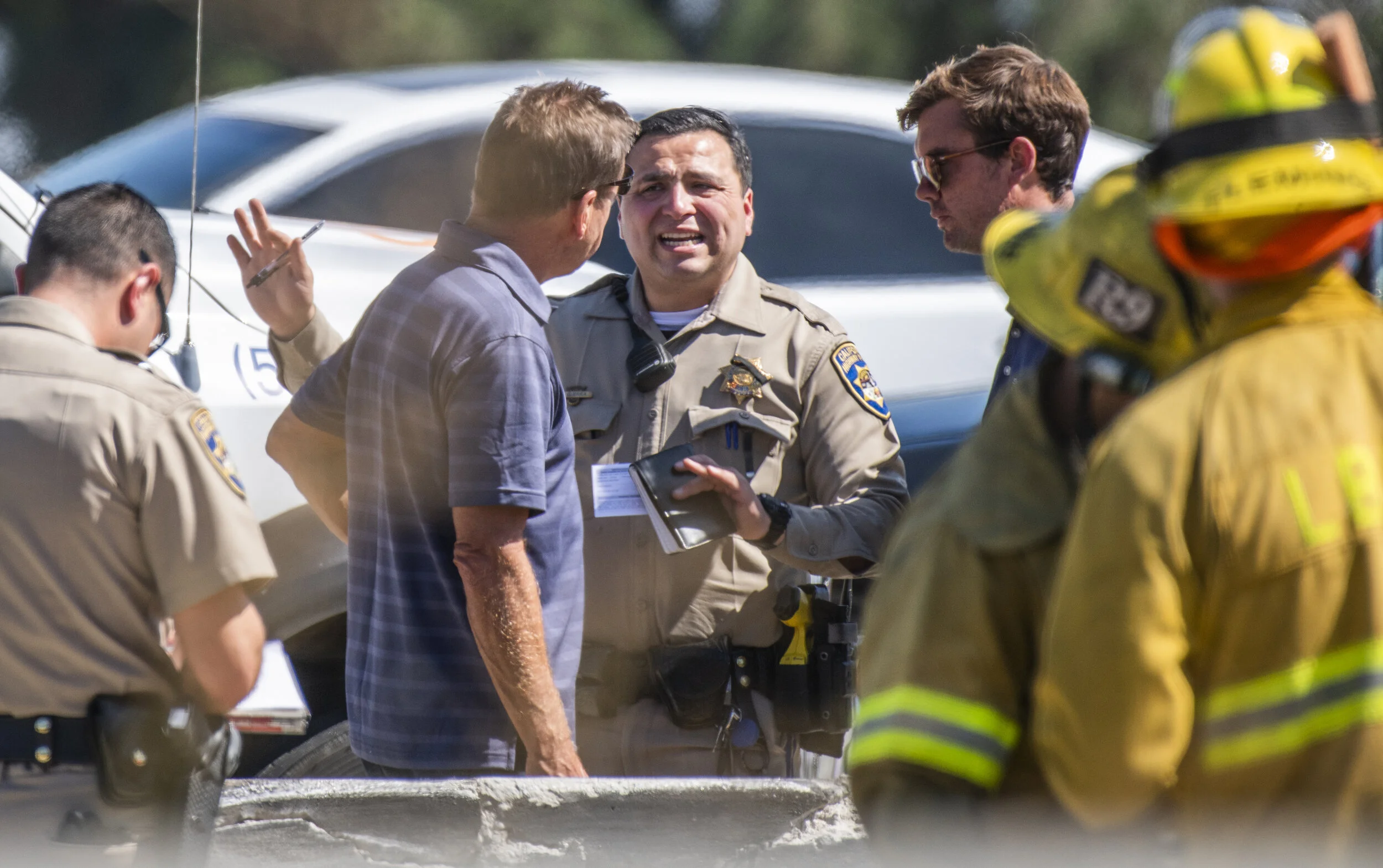  A CHP police officer talks with two drivers after a big-rig crashes into the center divider and spills cargo onto 405 Freeway in Long Beach Tuesday, August 20, 2019. Fuel from the truck and a load of pipes it was carrying spilled into the lanes, acc
