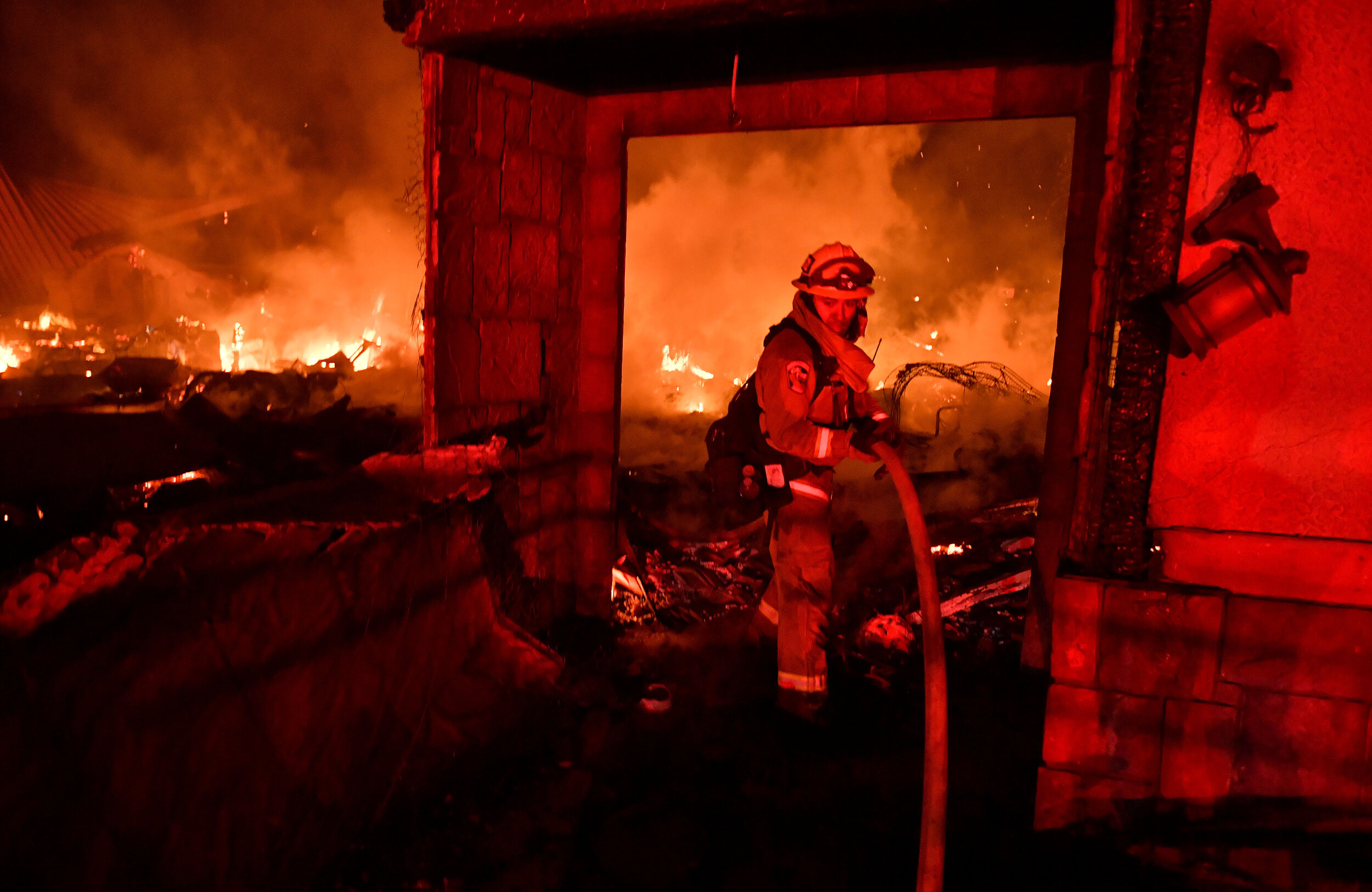  A firefighter works to extinguish flames at a home on Saturn Ct. in San Bernardino during the early morning hours of Thursday, Oct. 31, 2019 after the Hillside fire broke out in the early morning hours. At least 3 homes have been destroyed by the wi