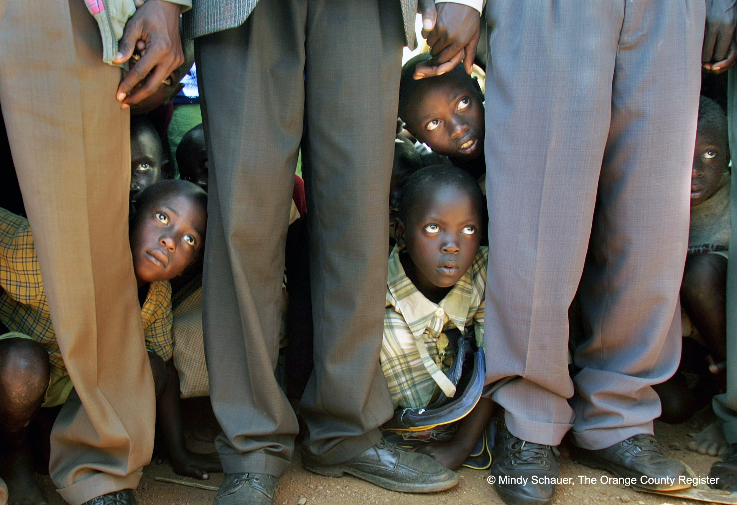   FACES:  Children take cover behind elders at Biharagu Primary, a crowded school of 1,815 students in Ruhuha. Saddleback members prayed after touring the facility that lacks a roof. ///ADDITIONAL INFO:warrenday1.pxx.ms.4.jpg - 07/28/06 - Photo by Mi