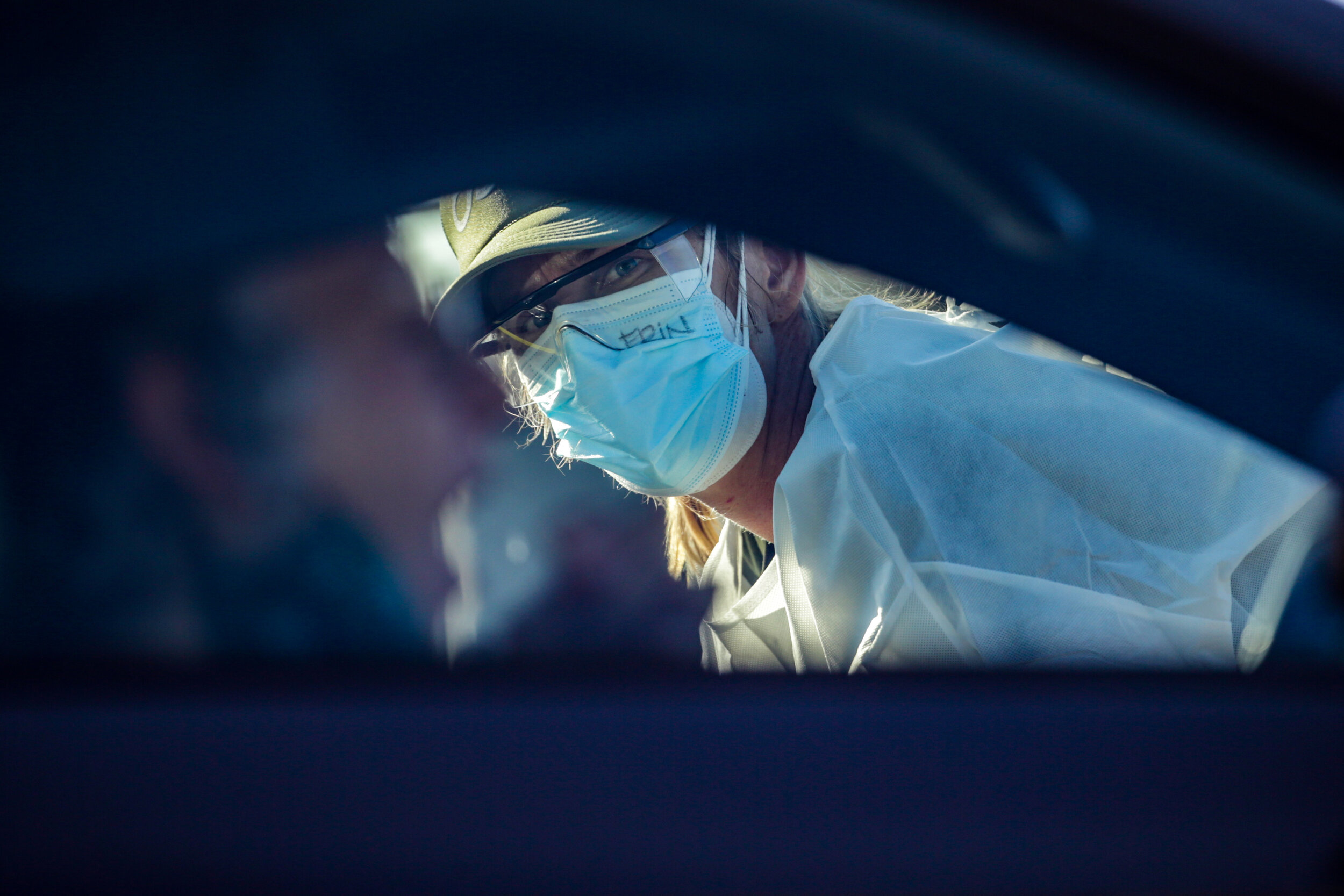  Los Angeles, CA, Wednesday, November 11, 2020 - A volunteer looks on as a man swabs his mouth at a drive by Covid-19 testing site.  According to the Atlantic, Covid Tracking Project, nearly 2 million Americans are tested daily.  