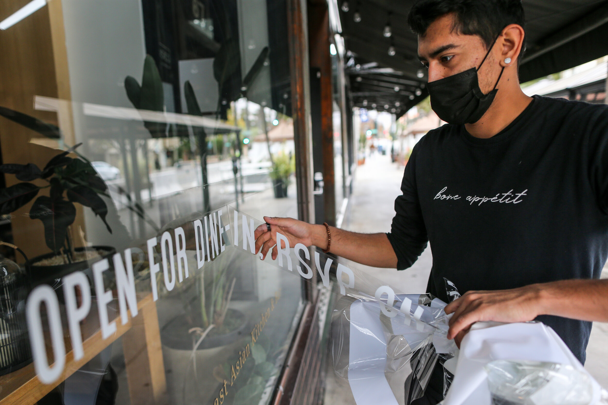  Pasadena, CA, Monday, Dec. 7, 2020 - Bone Kettle employee Joe Delgado removes a “we’re open for dine in” decal from the front window of the restaurant as state mandated covid-19 restrictions forbid outdoor dining.  A Bloomberg News article reported 