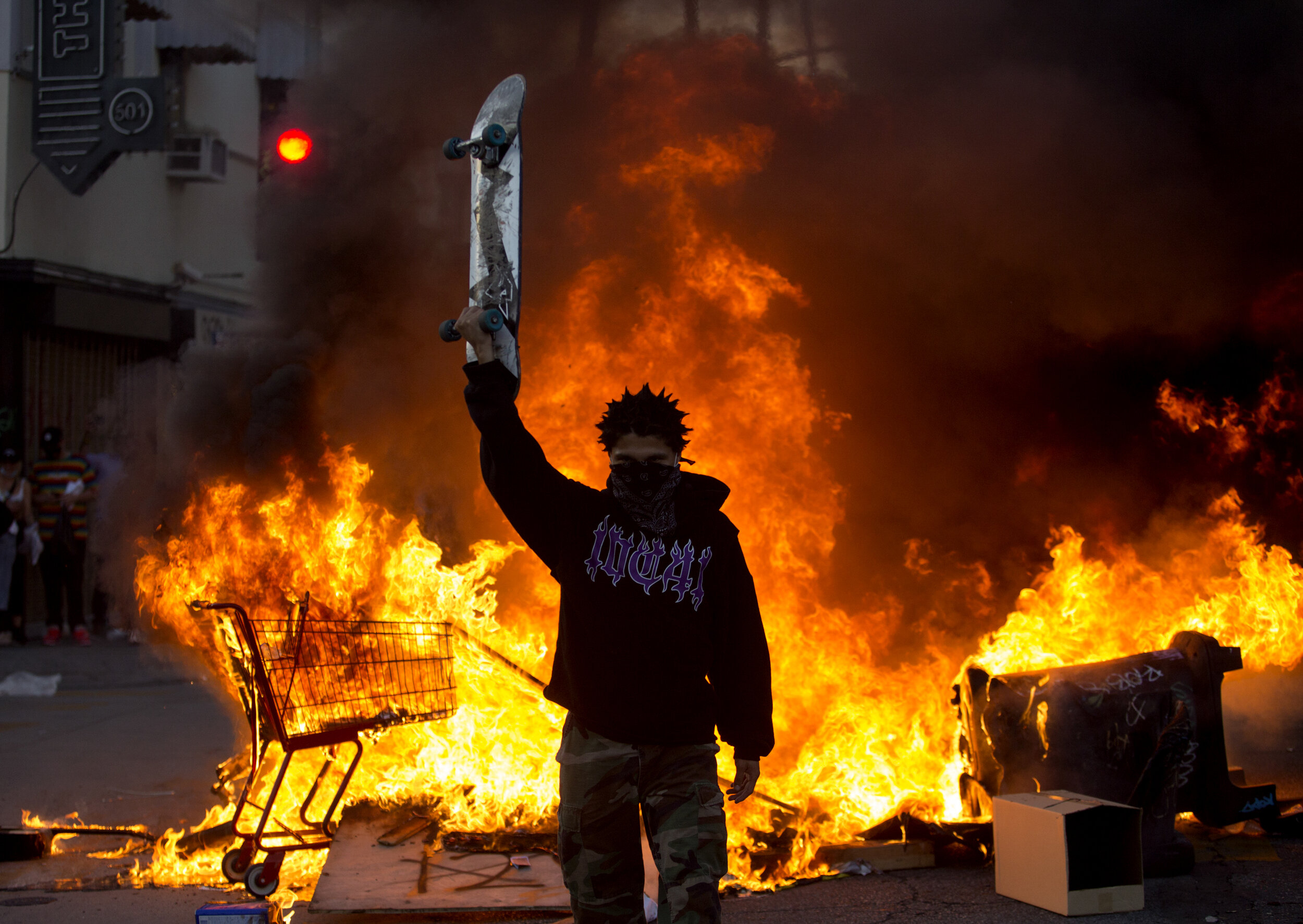 A protester holds a skateboard in front of a fire during a protest over the death of George Floyd, a handcuffed black man in police custody in Minneapolis, in Los Angeles, Saturday, May 30, 2020.The 2020 Black Lives Matter protests across the nation