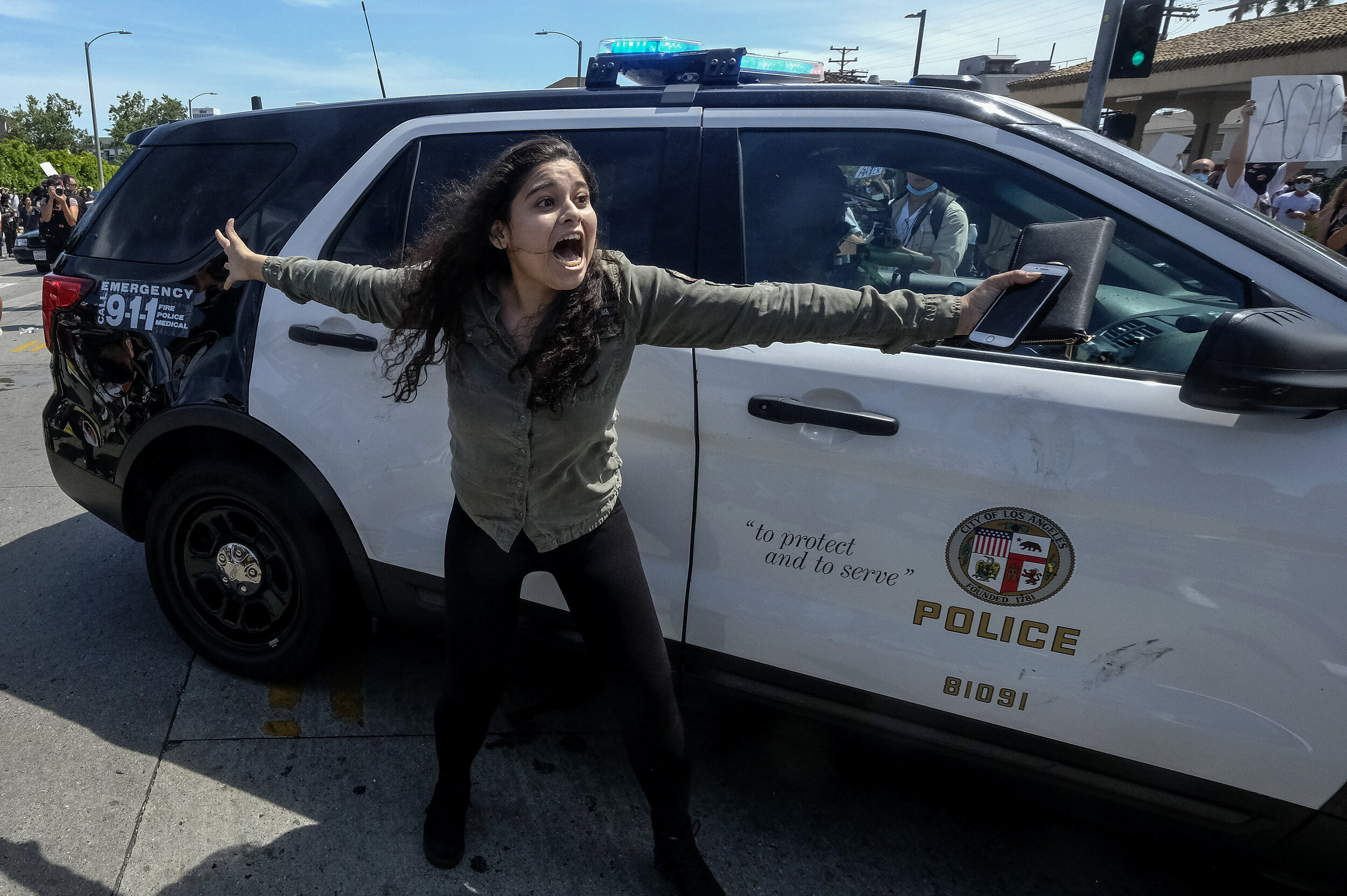  A protester tries to stop others from attacking a police vehicle during a protest over the death of George Floyd in Los Angeles, Saturday, May 30, 2020. Protests across the country have escalated over the death of George Floyd, a black man who was k