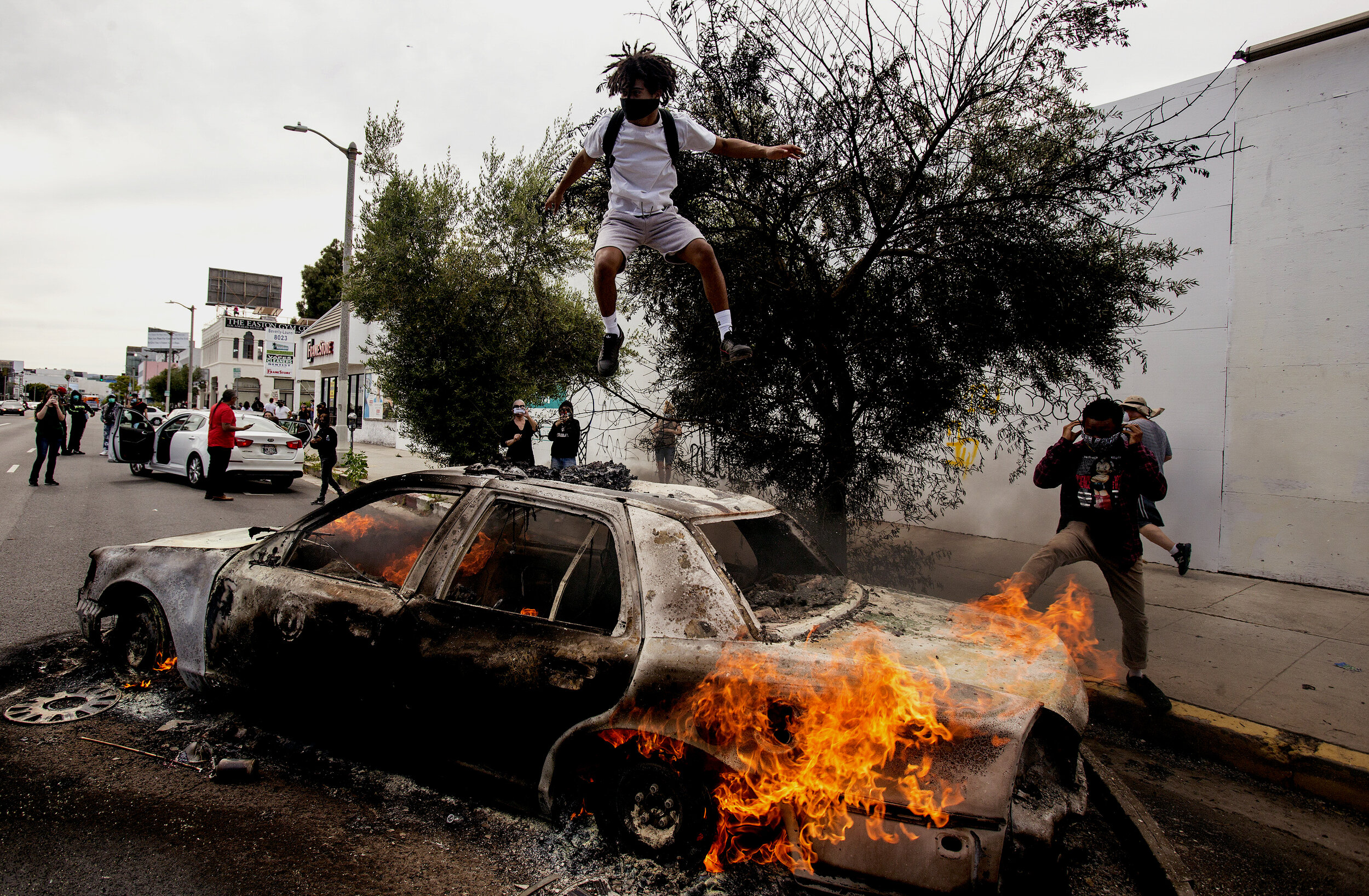  A man jumps on a burning police vehicle in Los Angeles, Saturday, May 30, 2020, during a protest over the death of George Floyd. Floyd died in Minneapolis police custody on Memorial Day.The 2020 Black Lives Matter protests across the nation were spa