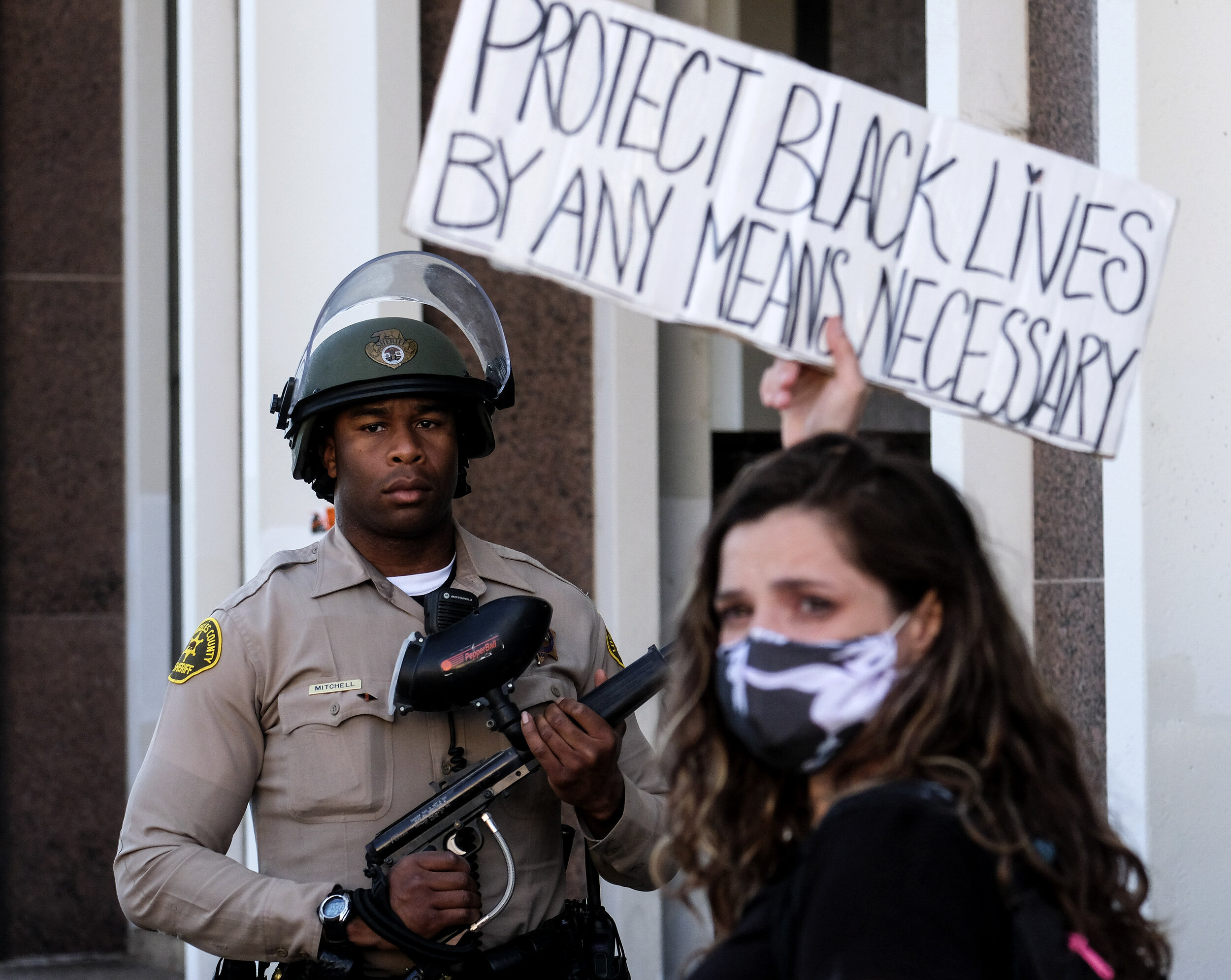 A demonstrator holding a sign stands against a Los Angeles County sheriff's deputy in a protest against the death of 18-year-old Andres Guardado and racial injustice in Compton, California, U.S., June 21, 2020.The 2020 Black Lives Matter protests ac