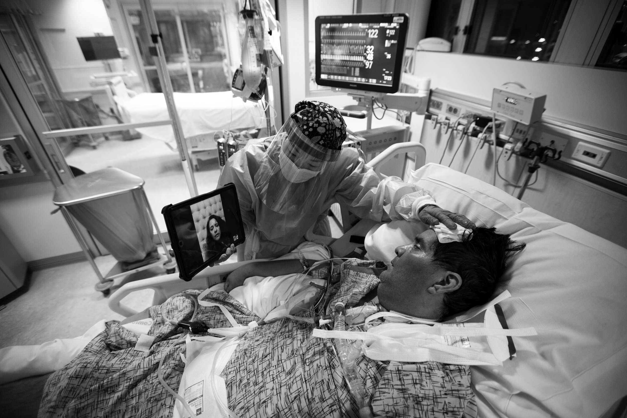   Registered Nurse Kat Yi holds an iPad up to Eduardo Rojas so that his wife Angelica Rojas inside the ICU at Providence St. Jude Medical Center Christmas Day on Friday, Dec. 25, 2020 in Fullerton, CA. Eduardo Rojas is a covid patient. His fever is r