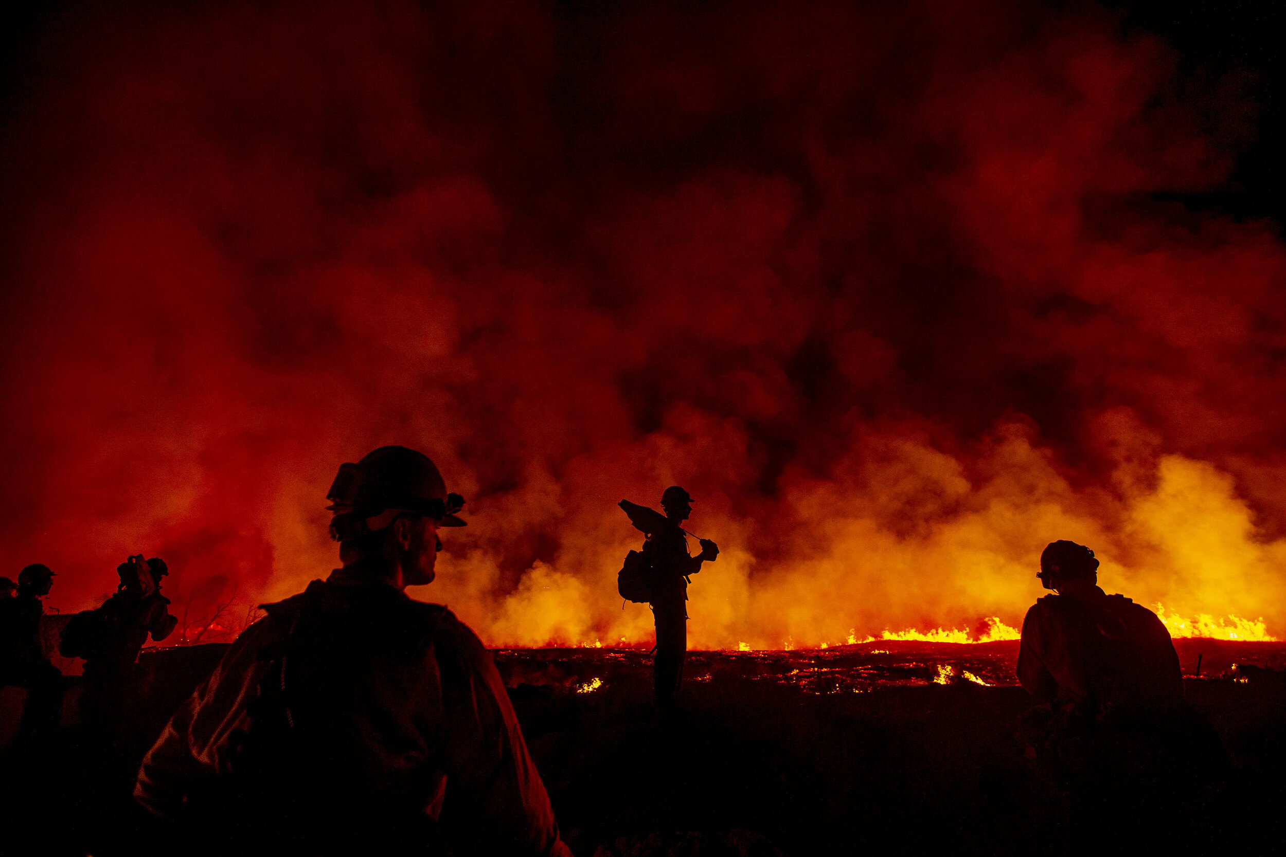  Arroyo Grande Hotshots are silhouetted as they watch the backfire they set to burn off 100 aches of brush to protect homes near the fire line at Carter Street and Bears Den Ranch Road in Yucaipa on Sunday, September 6, 2020.  