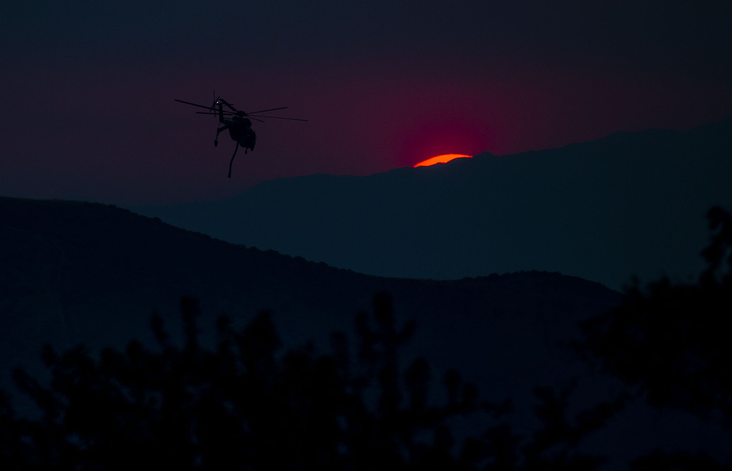  A water dropping helicopter heads back to refill for another drop on the El Dorado Fire as the sun sets in the heavy smoke in Yucaipa on Sunday, September 6, 2020.  