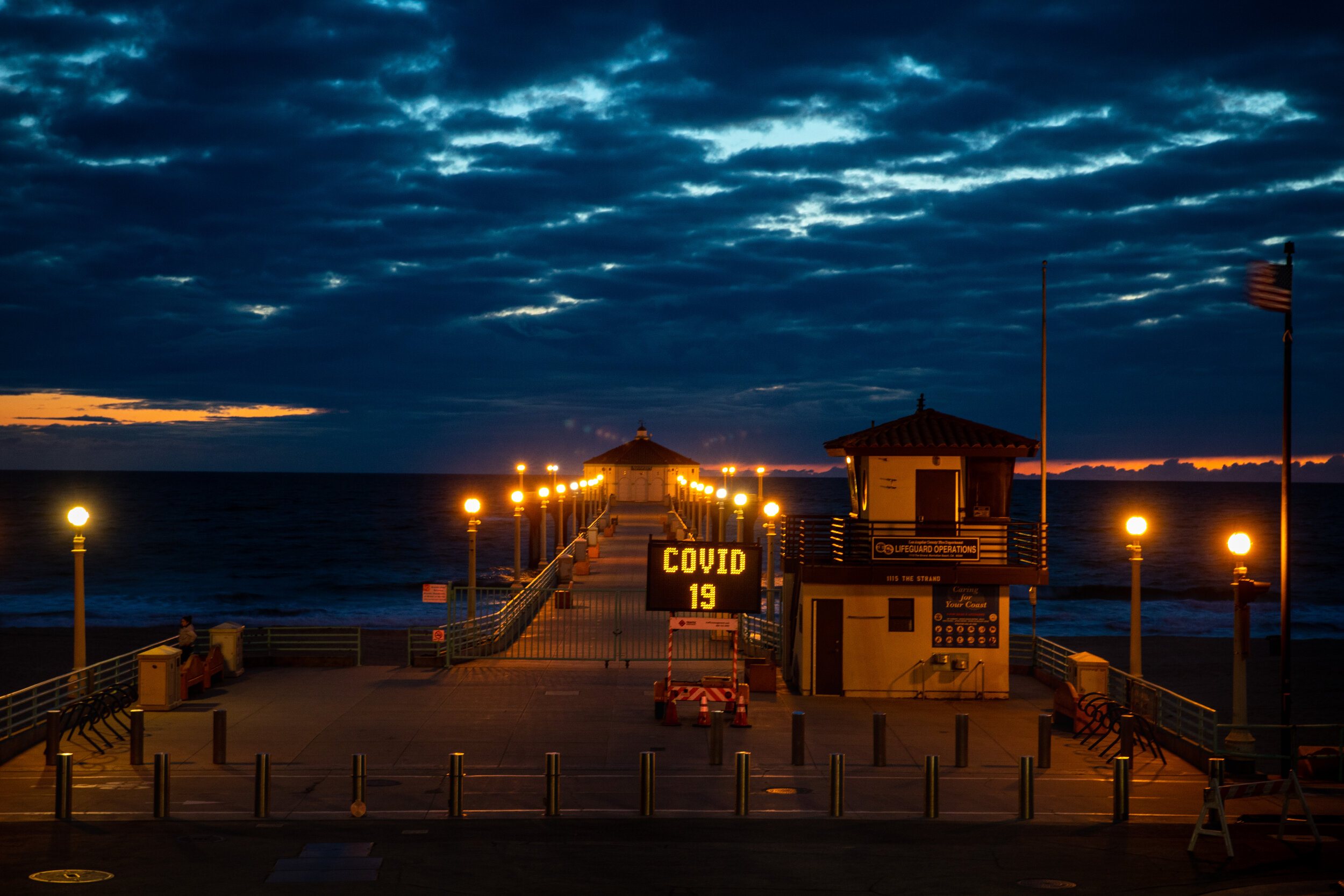  The Manhattan Beach, CA, Pier is gated and locked and a city maintenance sign repeats the message that (parking) “LOT CLOSED,” “COVID 19” and “Social Distancing,” the evening of March 25, 2020.  