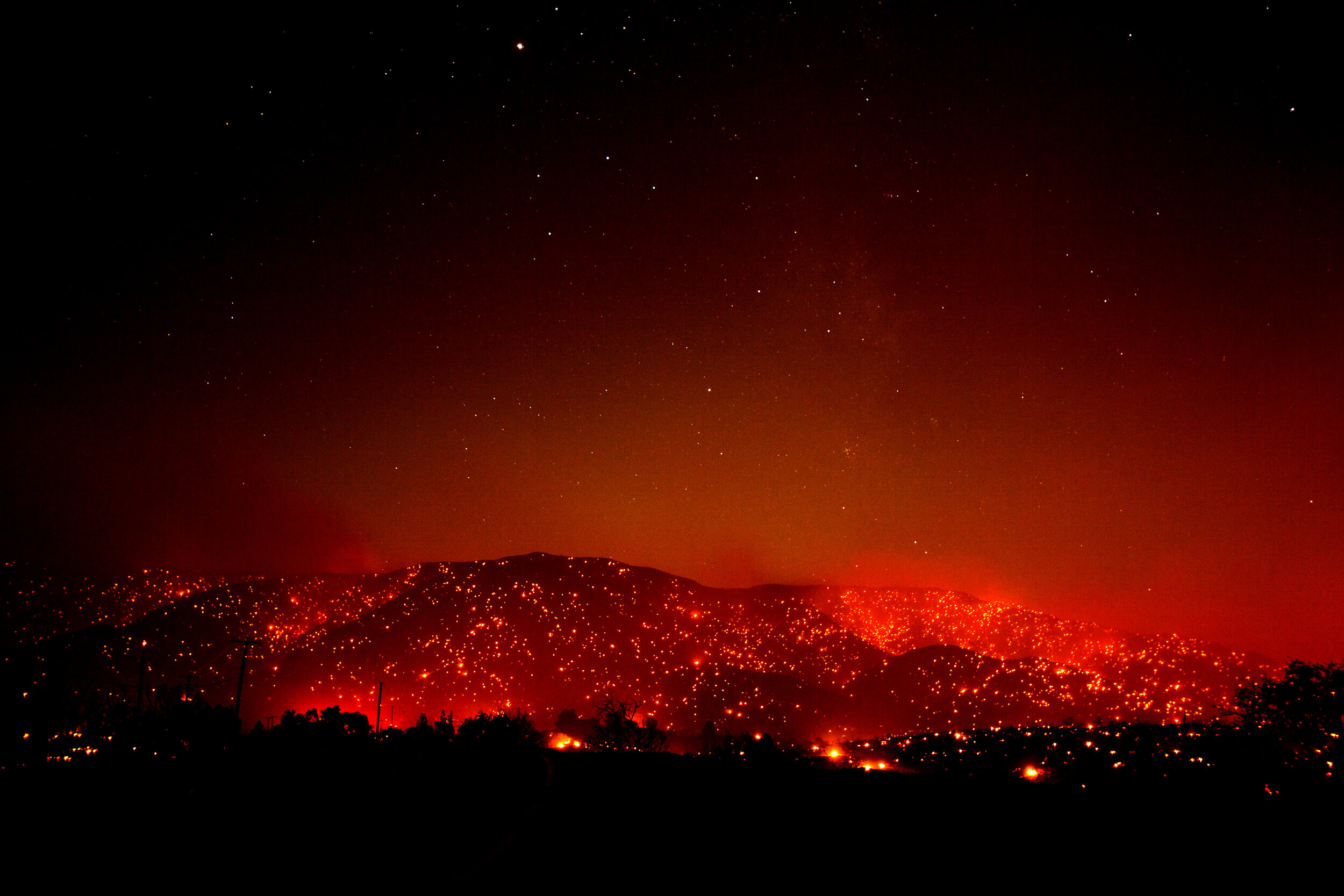  Flames dot a hill under a smoky sky from the Bobcat Fire in Juniper Hills, Calif., Friday, Sept. 18, 2020. The 2020 California wildfire season was characterized by a record-setting year of wildfires that burned across the state of California as meas