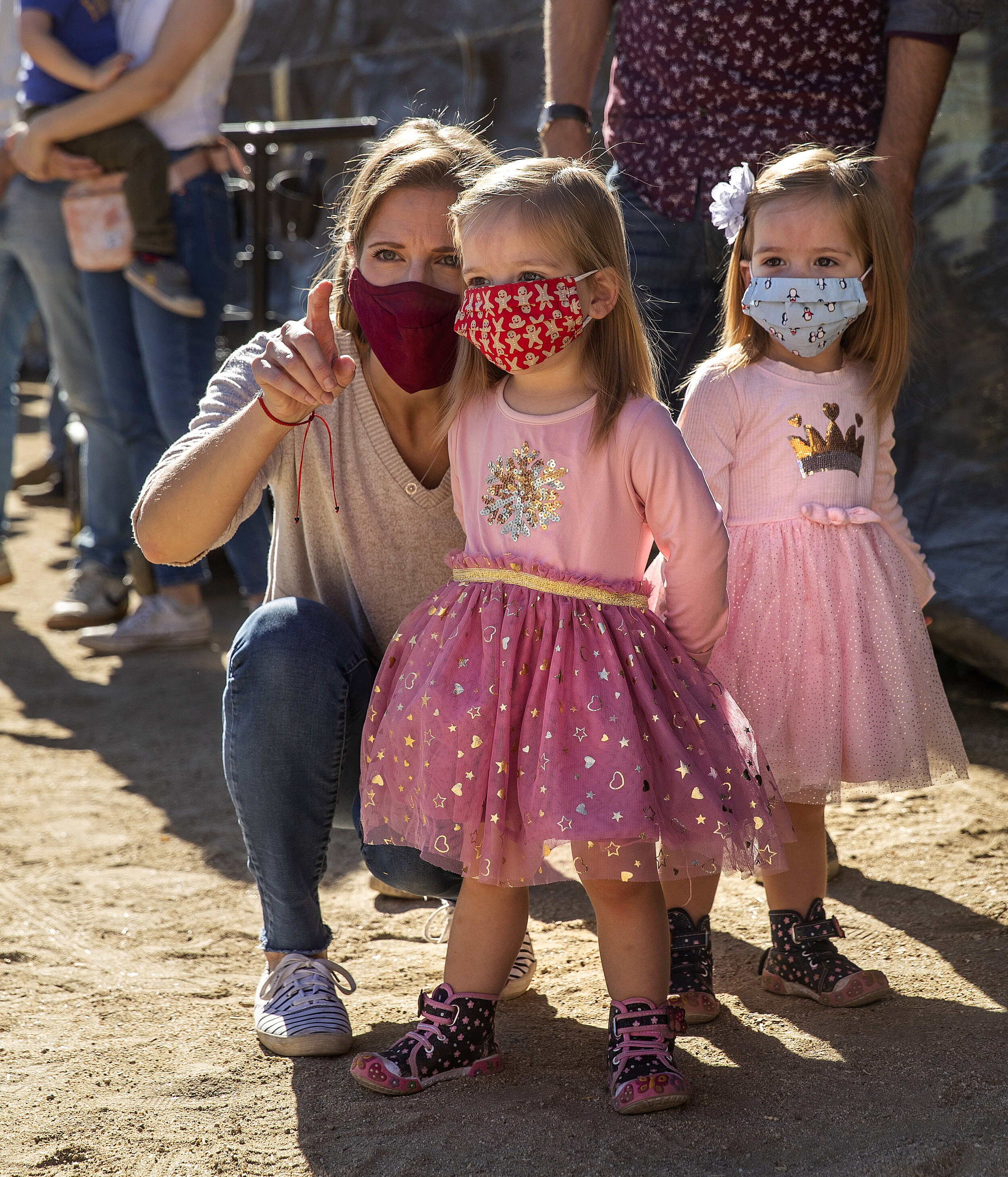  MOORPARK, CA - DECEMBER 05, 2020: Wearing protective masks against the coronavirus, Kristen Vazquez of Los Angeles points out Santa Claus to her 2 year old twin daughters, Zoe Vazquez, center, and Stella, during a visit to Underwood Family Farms in 