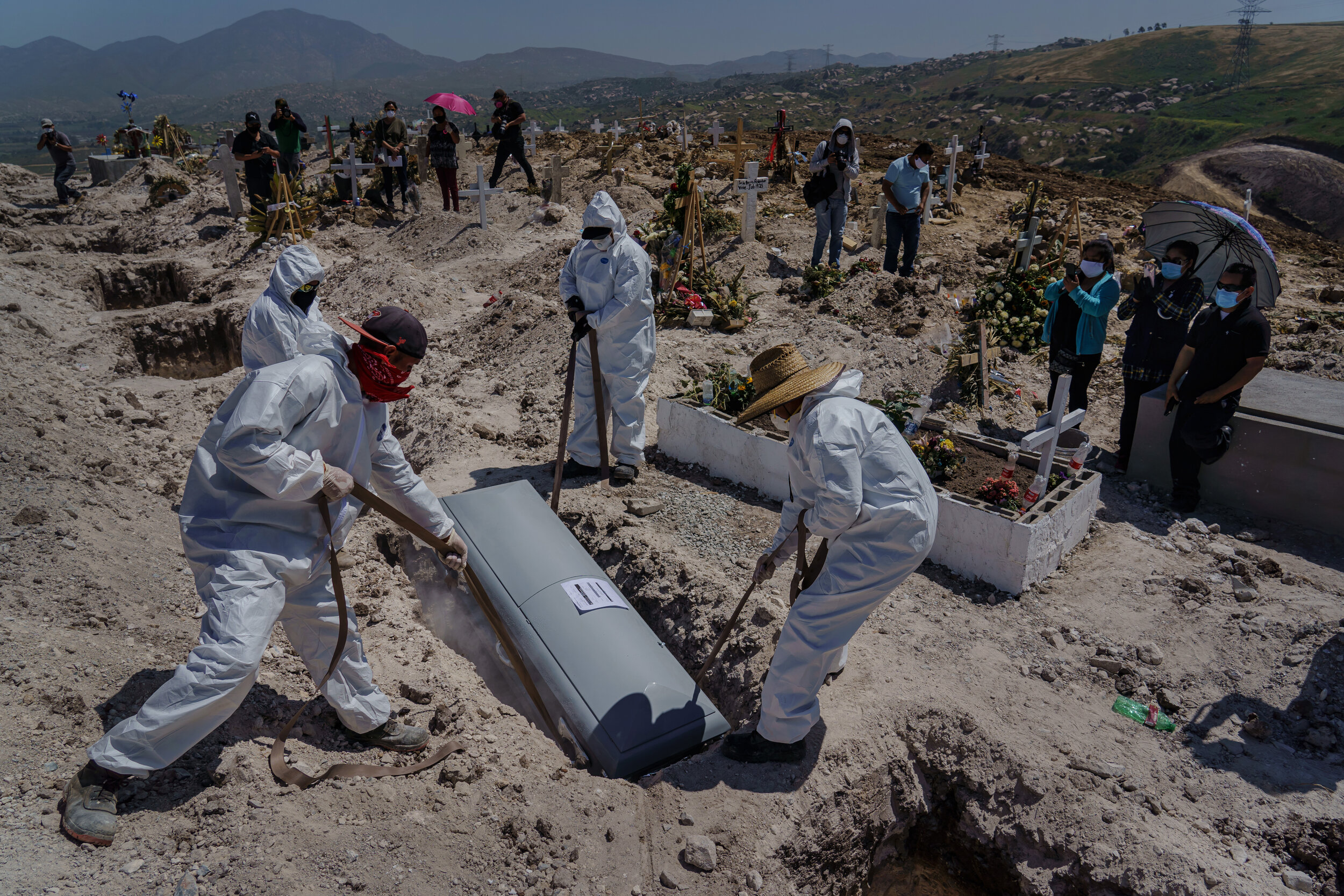  Cemetery workers lower the casket of Juan Velasco, who died of COVID-19 symptoms, as his family, to the right, watches the burial at the Municipal Pantheon 13 cemetery, in Tijuana, Mexico, on April 27, 2020. The coronavirus is killing so many people