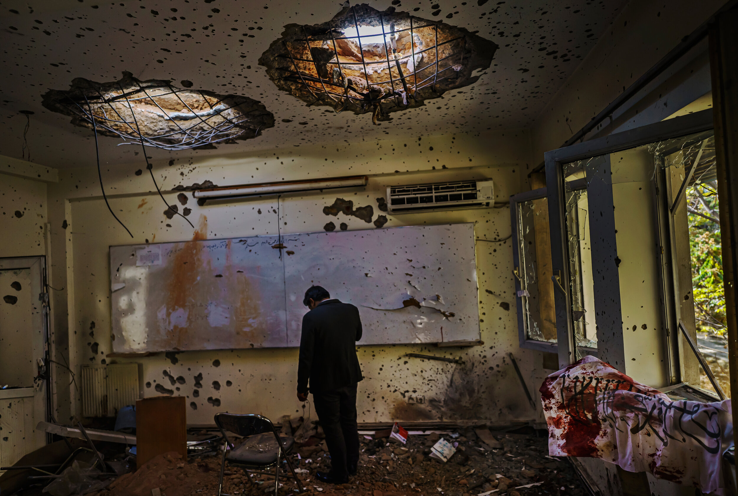  A man stands in the classroom and hangs his head low, in the aftermath of an attack on Kabul University, Afghanistans largest university, where three gunmen fired weapons and detonated explosives, concentrating their attacks in the the law faculty b
