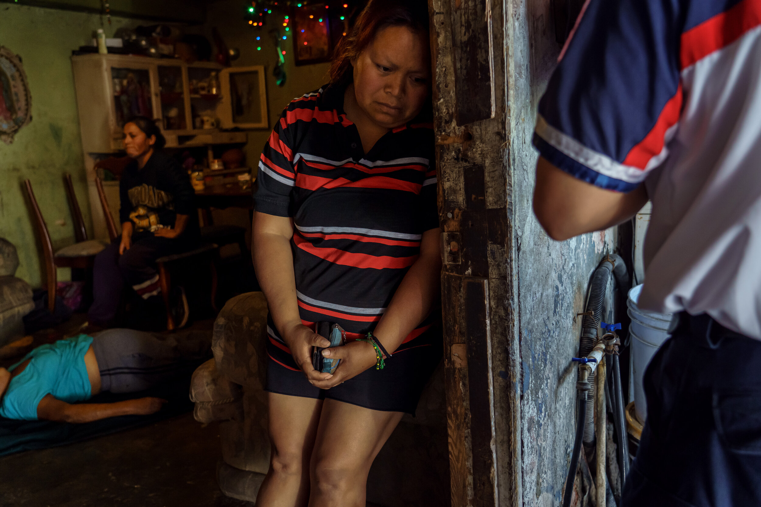  As Sergio Garcia stands in the doorway to calmly explain the next steps after death, Georgina Barajas Rios, grieves for her mother who just passed away, Maria Ruiz Olmedo, 71, after she suffered from symptoms that match COVID-19 symptoms, at their h