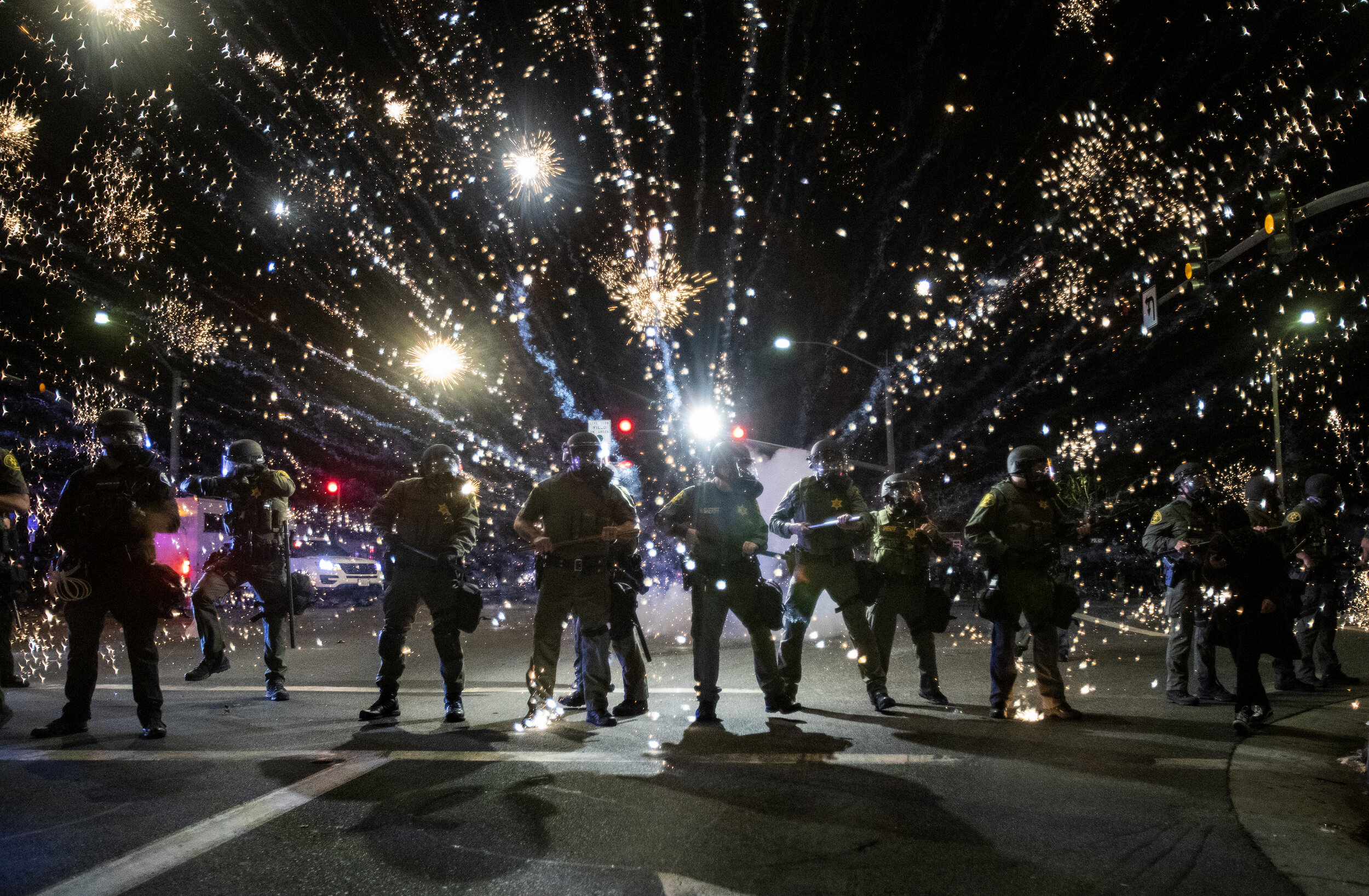  SANTA ANA, CA - MAY 30, 2020: Orange County Sheriff deputies maintain  a police block as a firecracker thrown by a protester explodes behind them during a protest against the Minneapolis police killing of George Floyd during the coronavirus pandemic