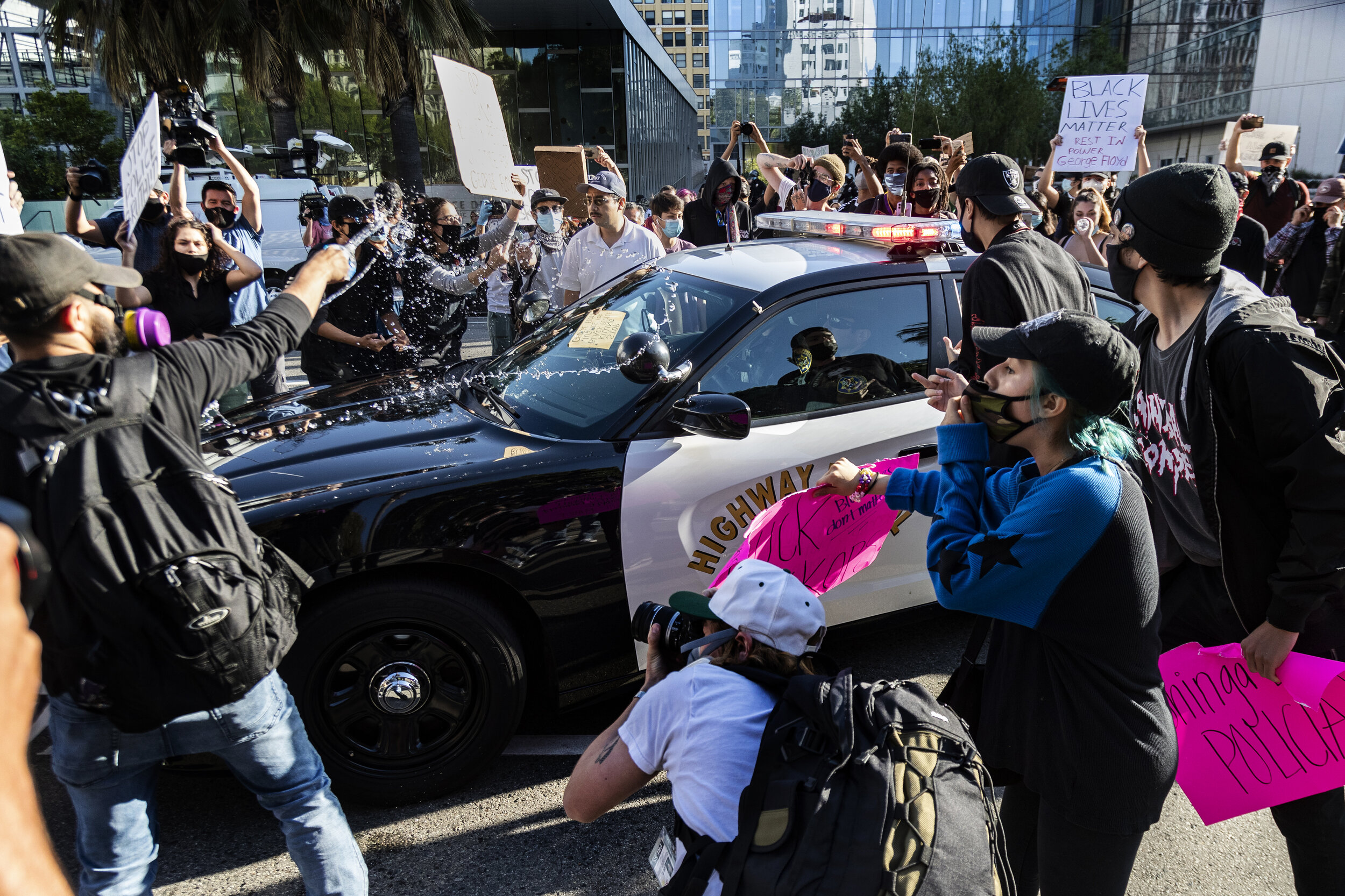  LOS ANGELES, CA - MAY 28, 2020: A protester tosses a bottled water on a CHP vehicle as other Black Lives Matter protesters swarm the car in a rally in front of LAPD headquarters to protest the death of George Floyd during the coronavirus pandemic on