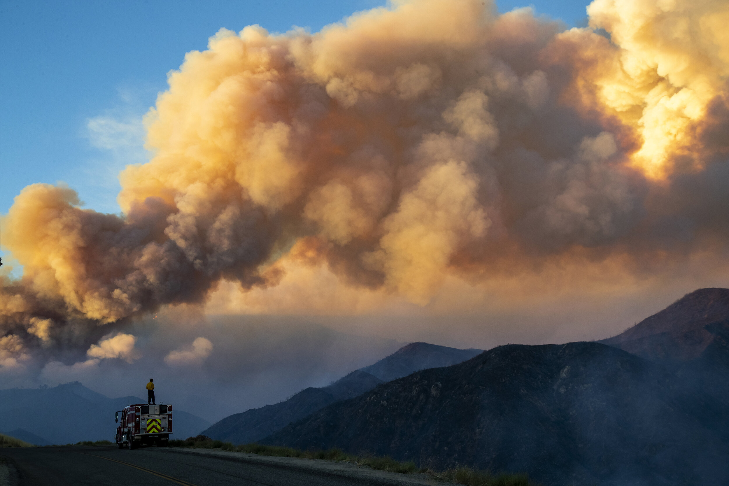  CHERRY VALLEY, CA - AUGUST 1, 2020: Firefighter Taylor Barnett from Carpinteria-Summerland Fire department monitors the huge plume from the out-of-control  Apple fire  north of Banning during the  coronavirus pandemic on August 1, 2020 in Cherry Val