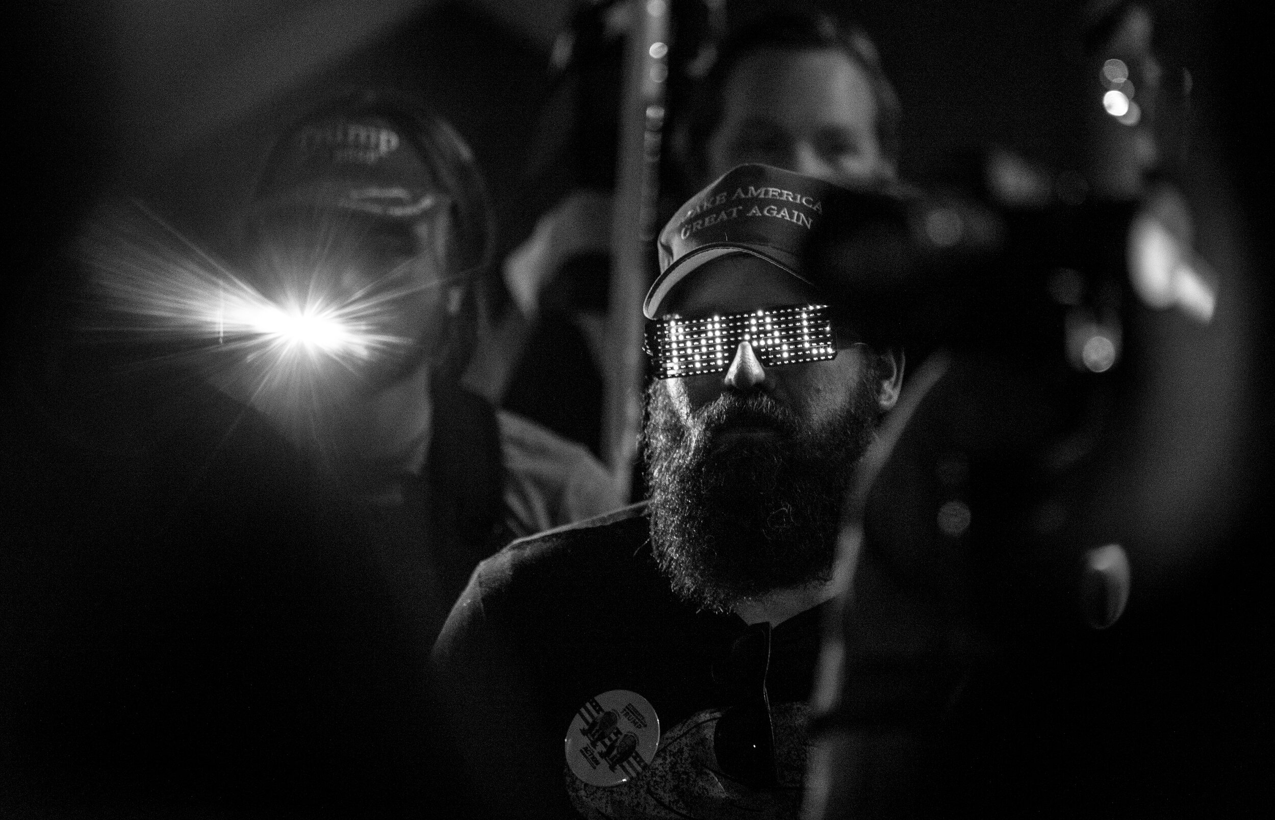  PHOENIX, AZ - NOVEMBER 5, 2020:  A Trump supporter wears glasses that illuminate the word “MAGA” while attending a “Stop the Steal” protest in the parking lot at the Maricopa  County Tabulation and Election Center as presidential ballots continue to