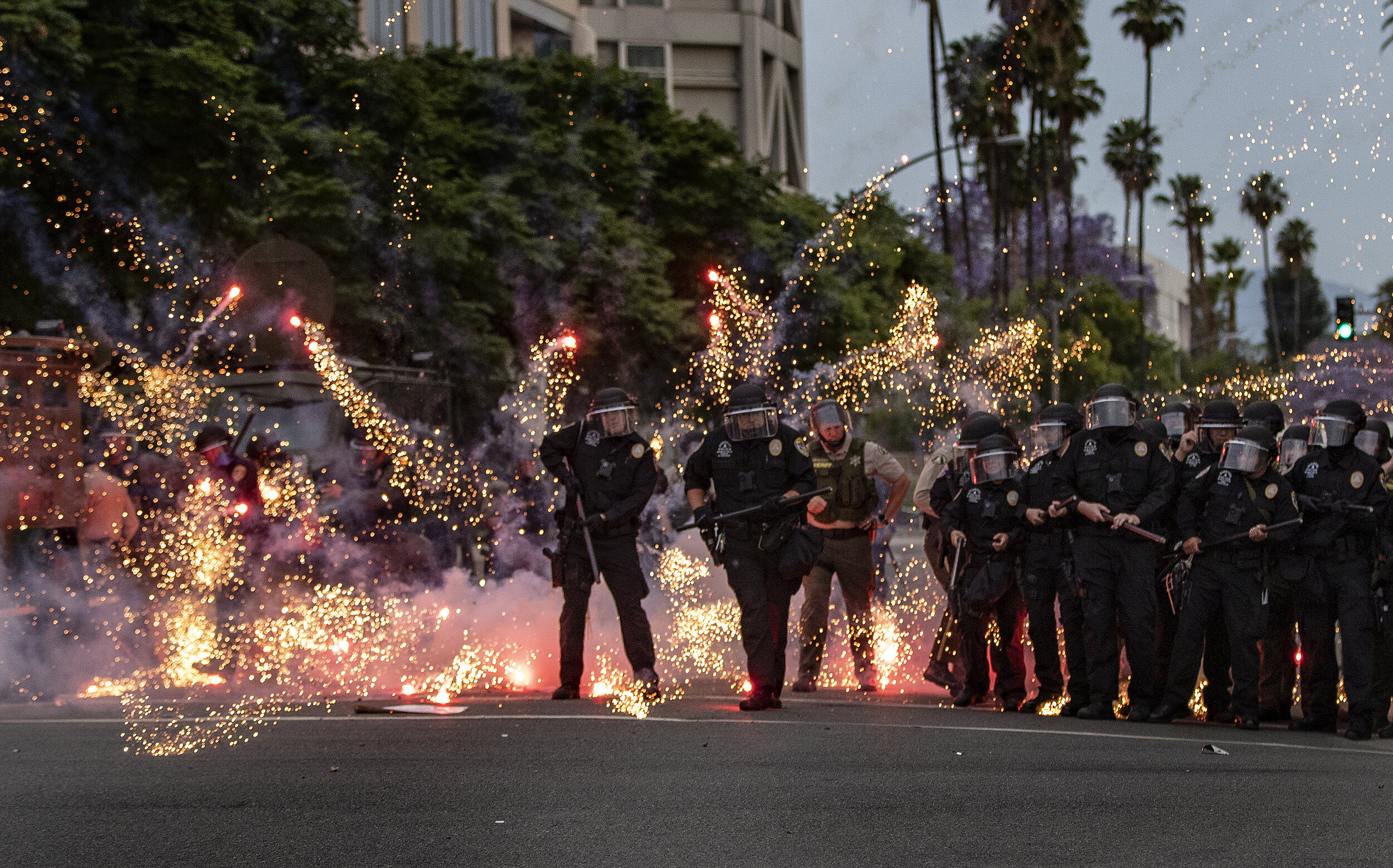  RIVERSIDE, CA - JUNE 1, 2020: Fireworks thrown by protesters explode at the feet of Riverside Police officers during a demonstration against the death of George Floyd during the coronavirus pandemic on June 1, 2020 in Riverside, California. Thousand