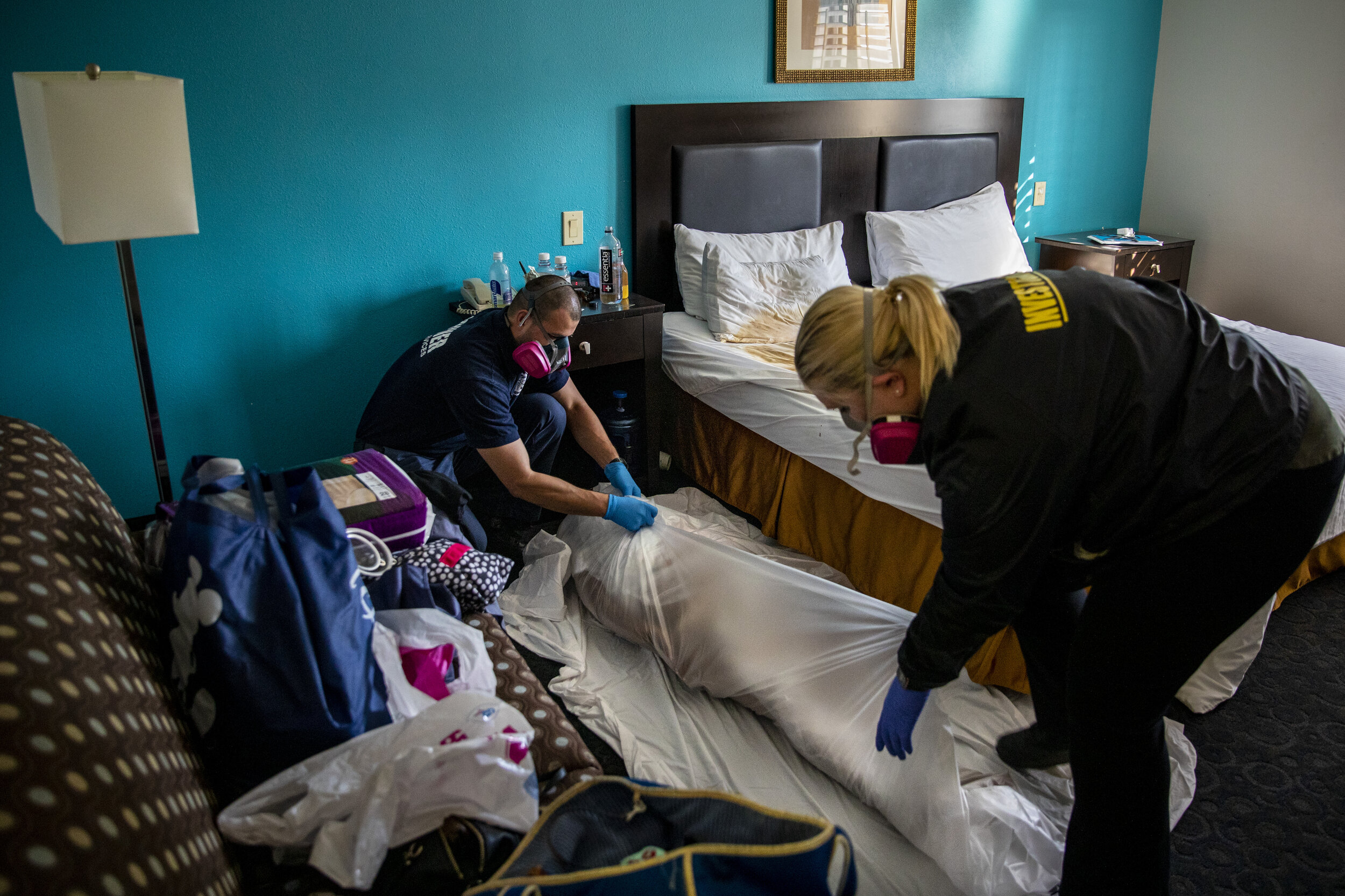   Kristina McGuire, an investigator with the Los Angeles County Dept. of Medical Examiner-Coroner, right and Jerry Meza, forensic attendant, prepare to transport the lifeless body of Judy Bounthong, 58, an ob-gyn tech at Emanate Queen of the Valley H