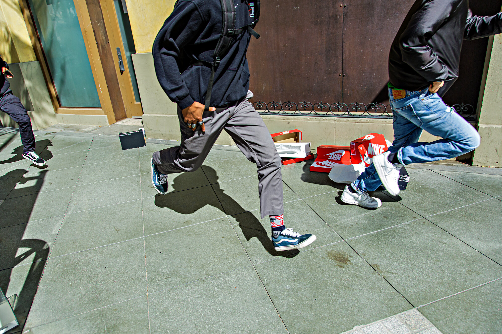  Young men run past empty boxes of looted shoes on Santa Monica Blvd., in Santa Monica, Calif., on Sunday, May 31, 2020. 
