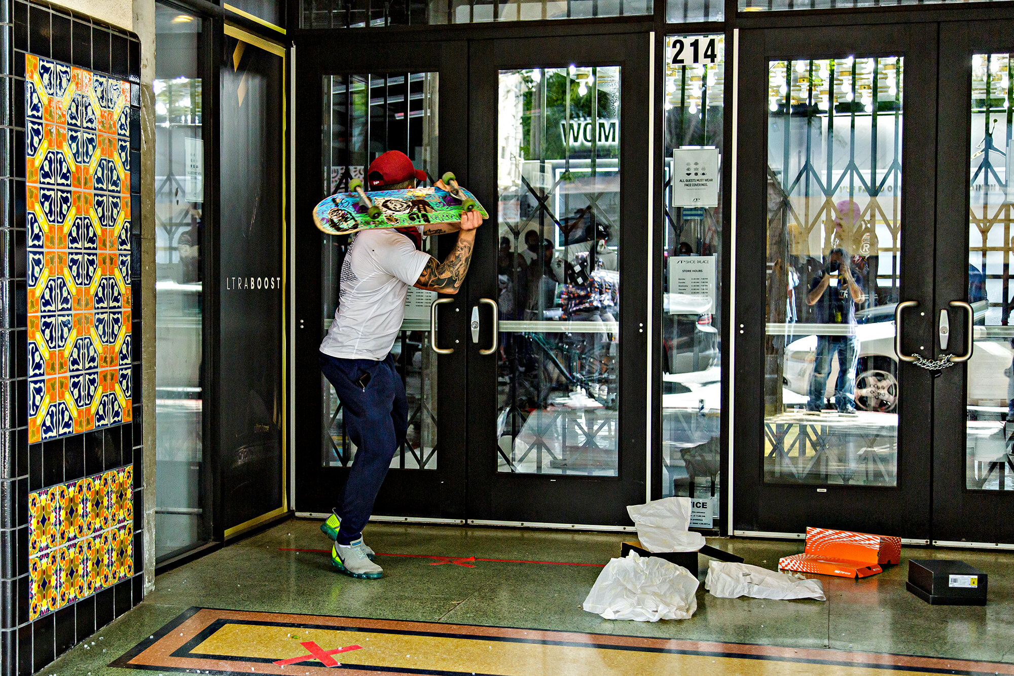  A man uses a skateboard to try to break into the Shoe Palace store on Santa Monica Blvd., in Santa Monica, Calif., on Sunday, May 31, 2020. 