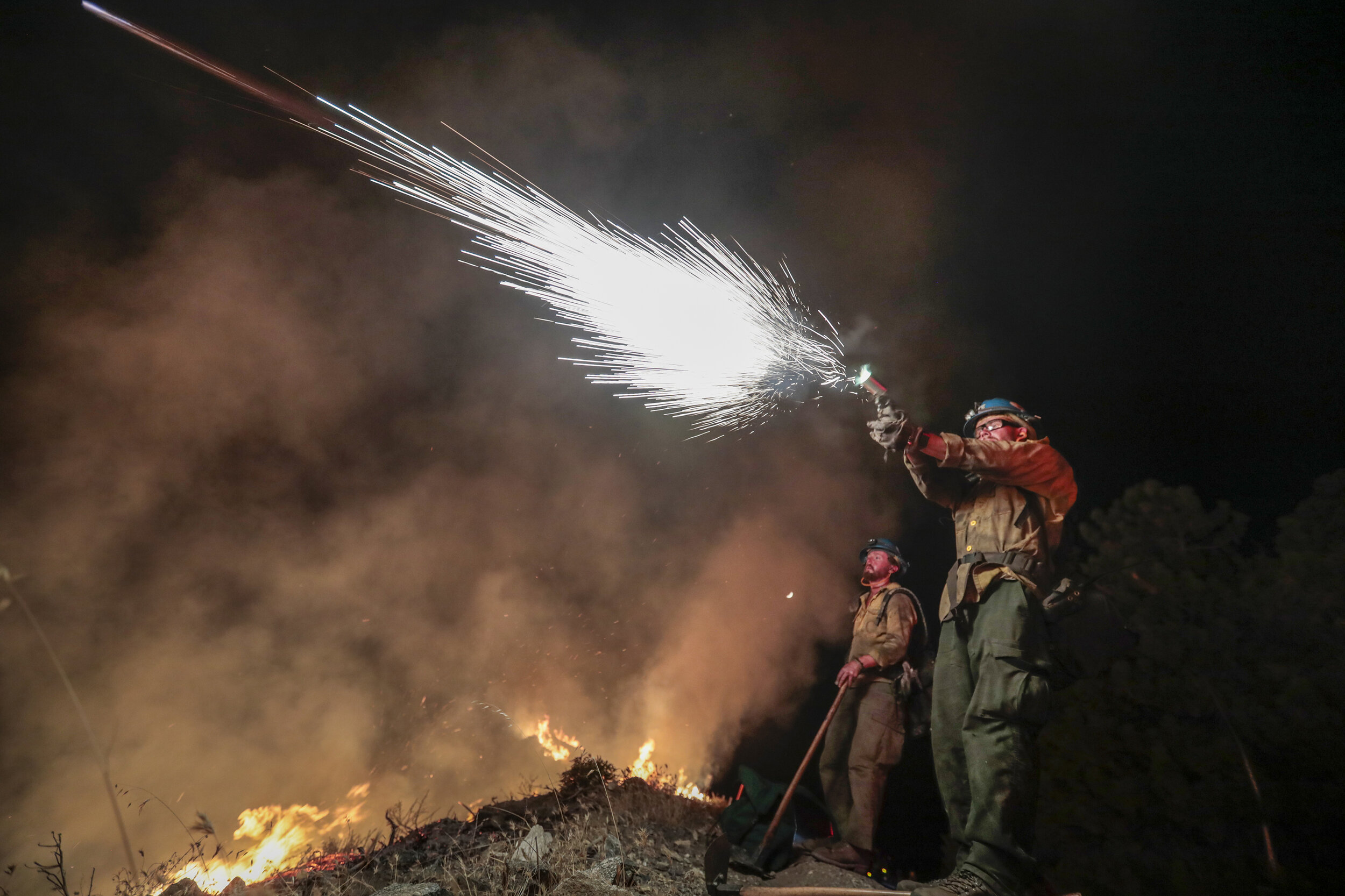  Blue Ridge, Arizona hotshot firefighter Keith Lemcke shoots a flare into dry brush as Kurt Mattocks supervises during a burn out operation on the Bobcat Fire. It was reported that nearly 3400 fire personnel were deployed throughout the country at th