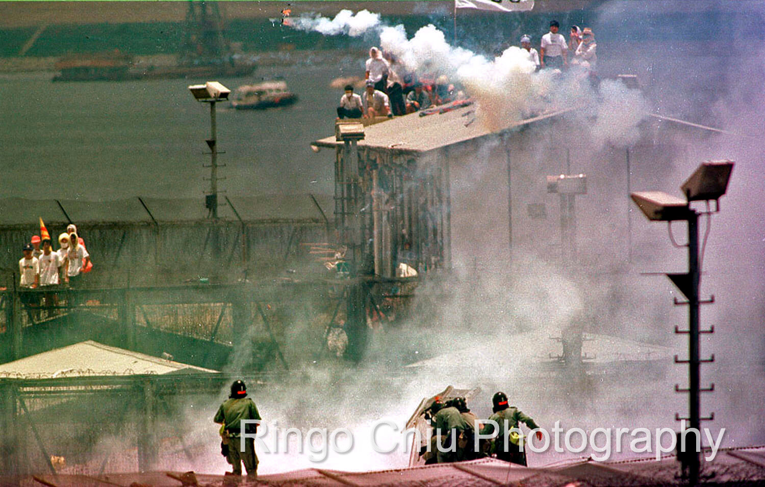  Police use tear-gas bomb to repress the Vietnamese boat people during a rooftop protest at Whitehead Detention Center in Hong Kong (1995) 