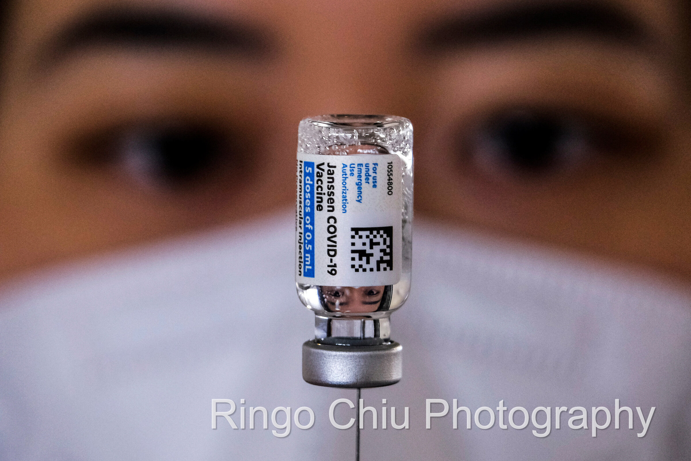  A health worker is projected on a vial of the new one-shot Johnson & Johnson COVID-19 vaccine at a vaccination site in Covina, California, on March 13, 2021. 